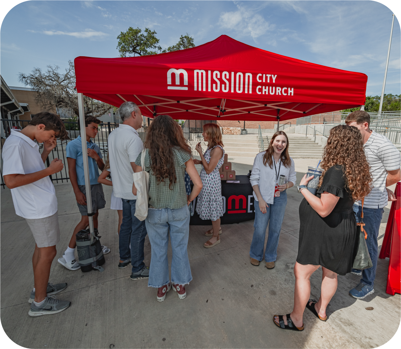 People gathered around a Diagnostic City Church booth under a red canopy outdoors on a sunny day