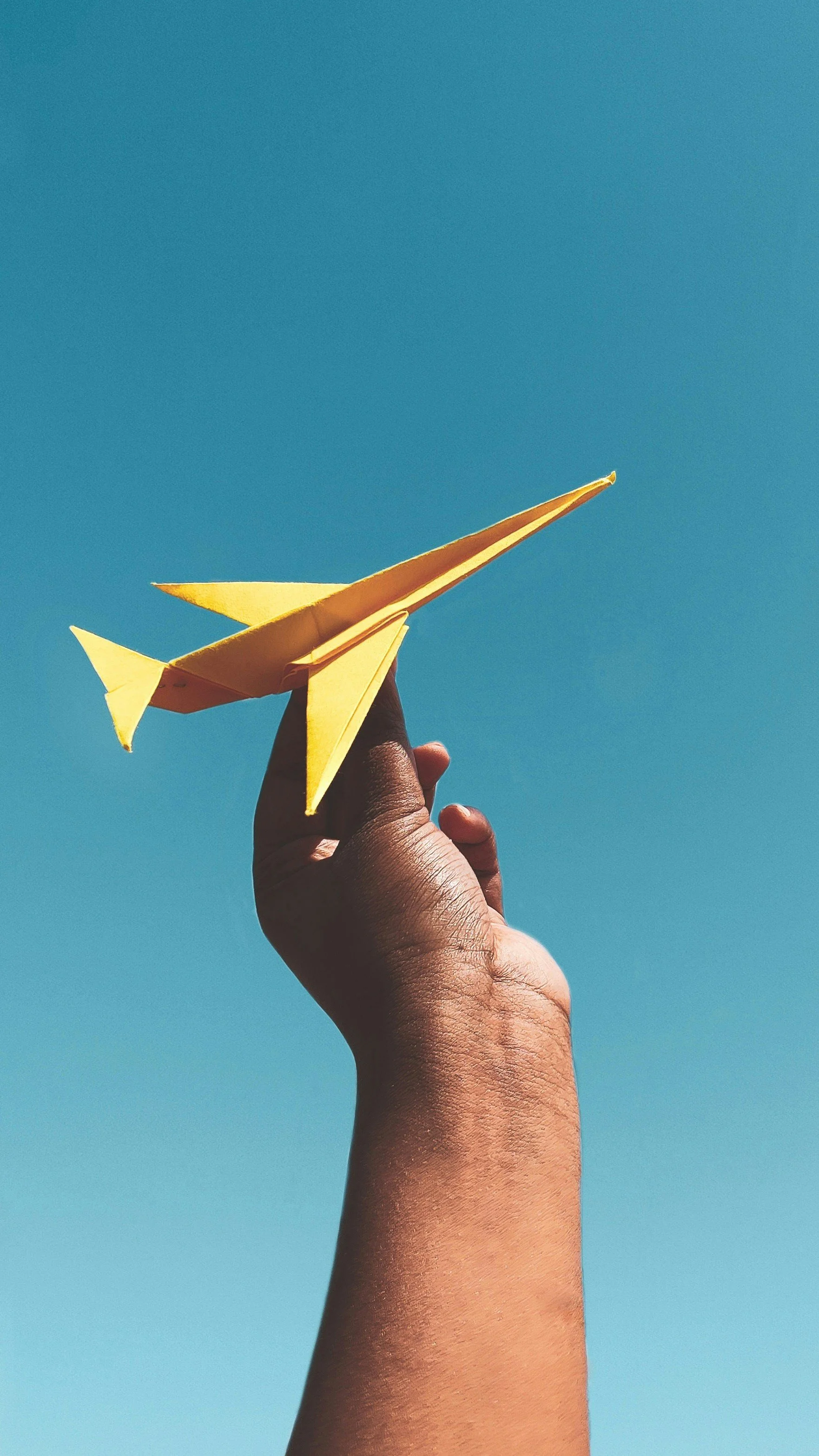 Hand launching yellow paper airplane – representing growth and coaching in motion