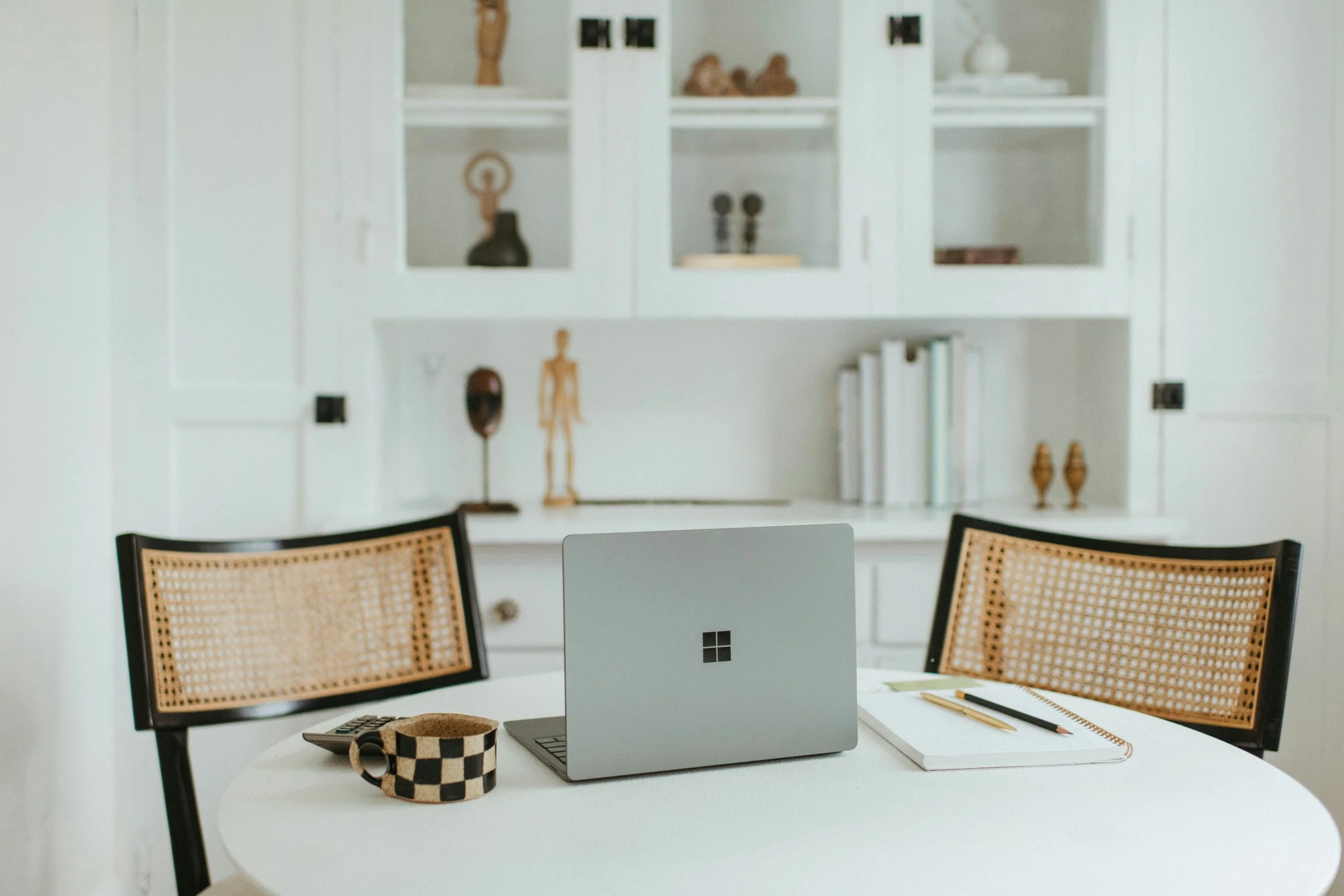 Desk with laptop, notebook, pen, and coffee mug in a modern home office