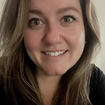 Close-up of a woman with long light brown hair smiling at the camera.