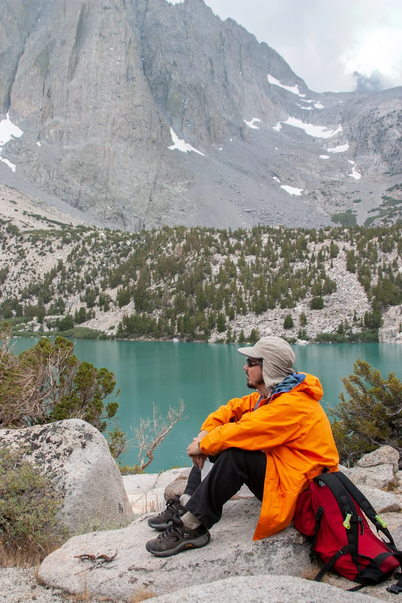 Proposed alt text: Kim Baumann Larsen sitting by an alpine lake in the California High Sierras, with granite peaks and pine forest in the background.