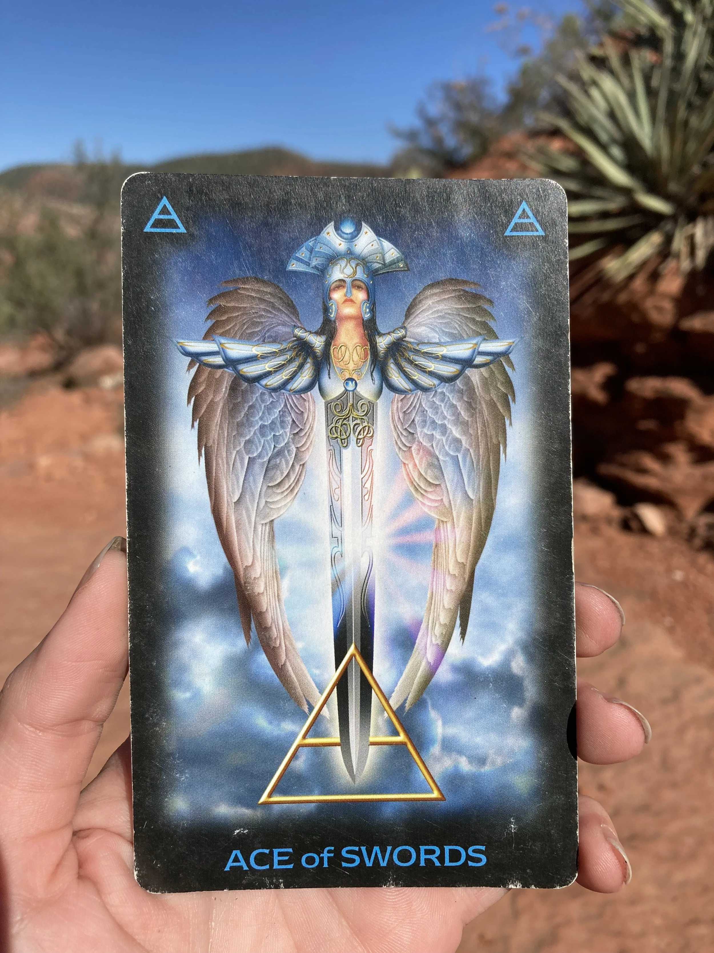 this image shows the ace of swords card, held in a hand in the desert outside Sedona, Arizona