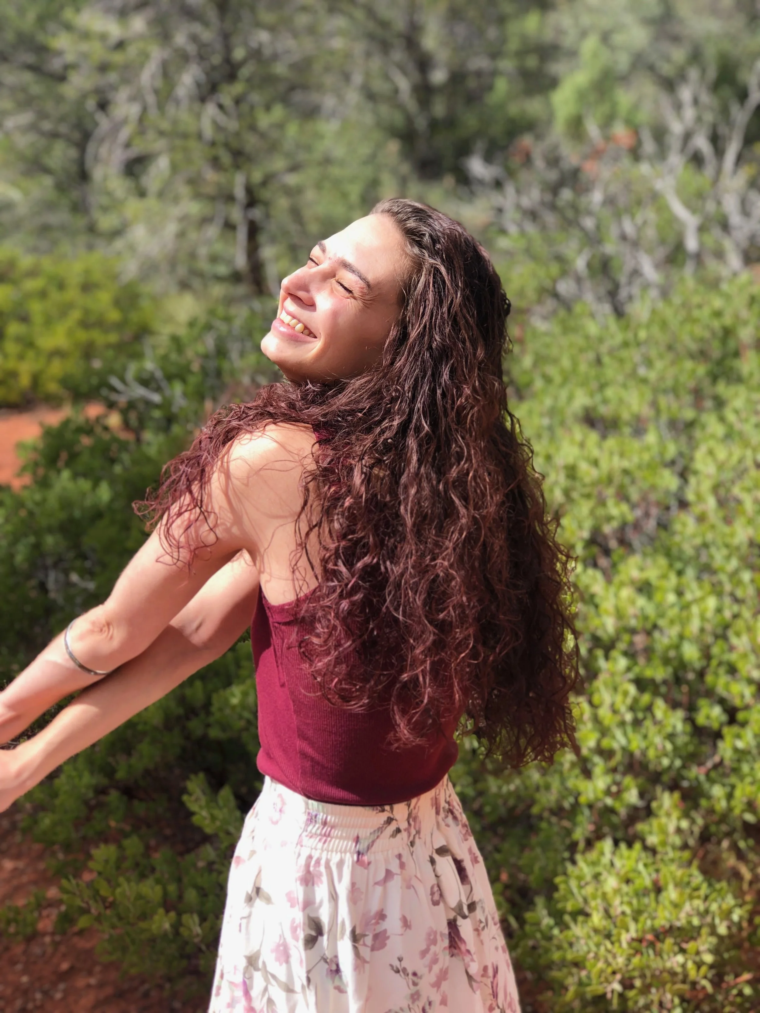 me smiling with the sun shining on my face and the green of the manzanitas in the background