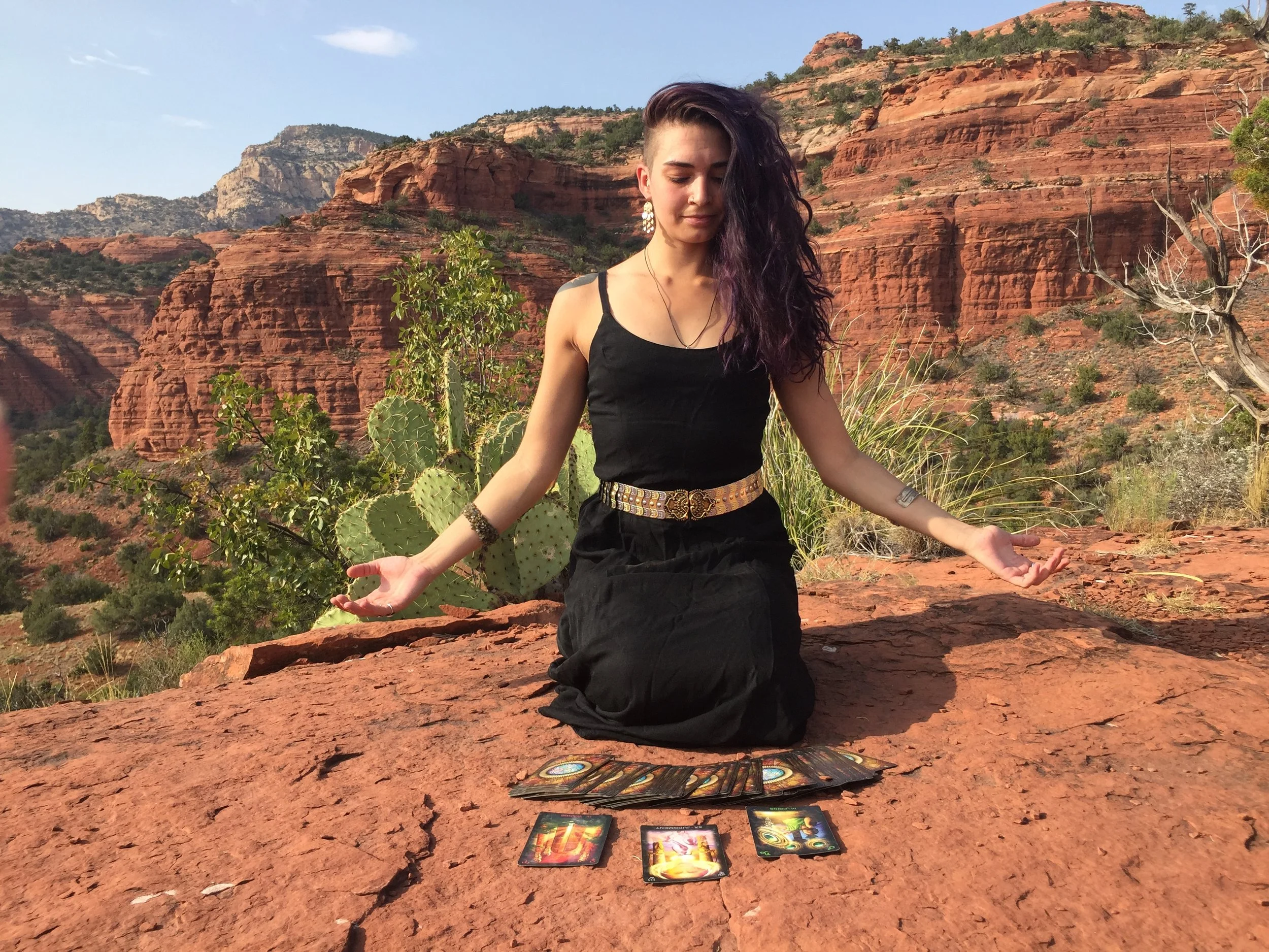 this is a photo of me opening to the cosmos on the red rocks with beautiful Sedona scenery in the background and my tarot deck in front of me