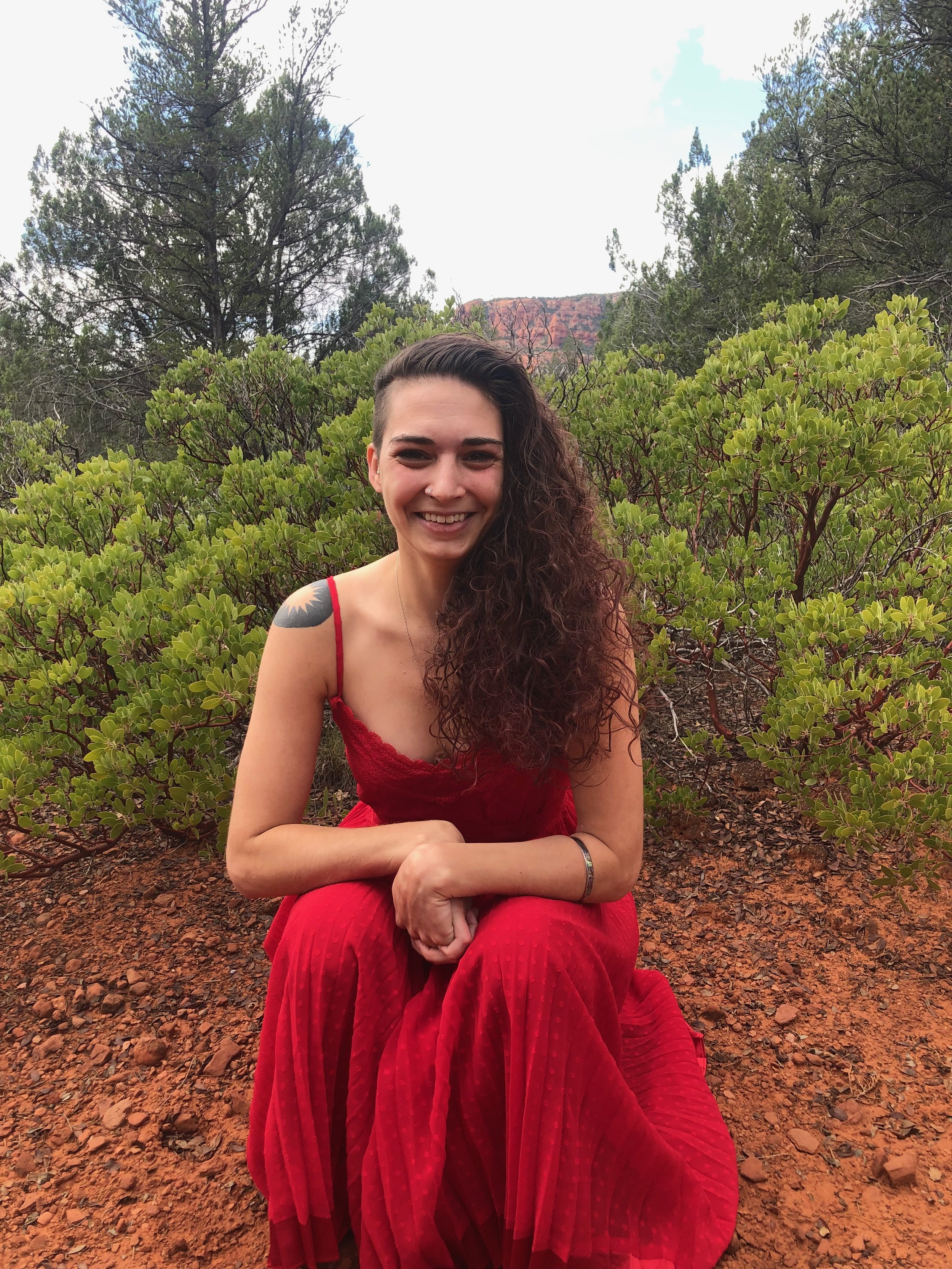 a photo of me smiling with the manzanitas and Sedona in the background
