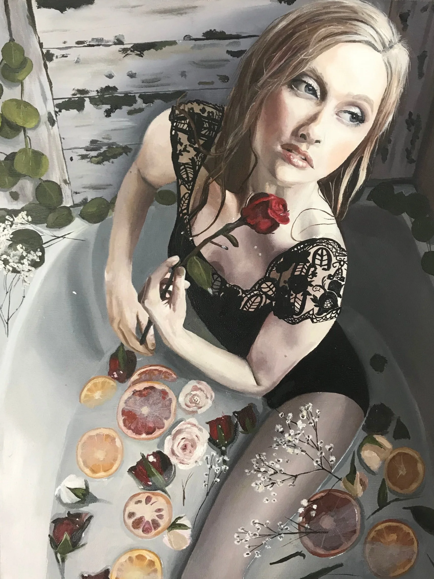 A woman with blonde hair and a black lace dress sitting in a bathtub filled with sliced oranges, strawberries, and flowers, holding a red rose.