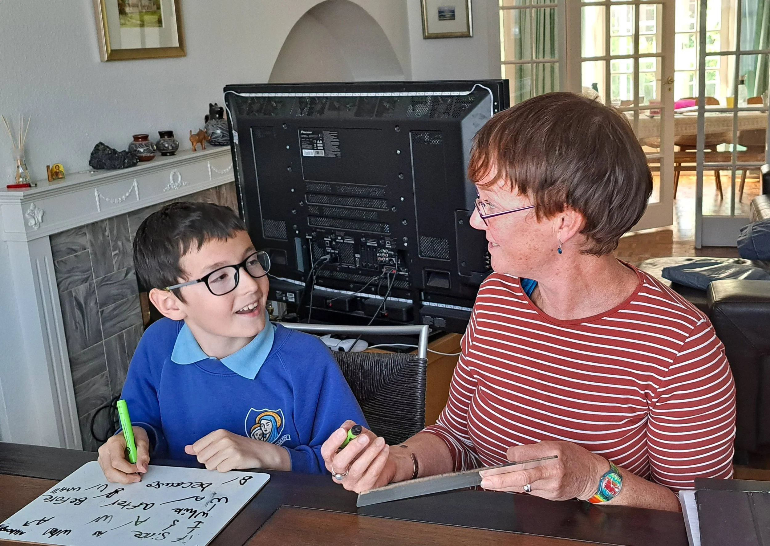 Heather teaching maths to a Year 6 student, smiling.
