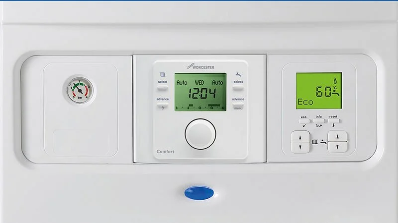 Close-up of a white central heating or boiler control panel with digital display showing 12:04, eco mode at 60°C, and pressure gauge.