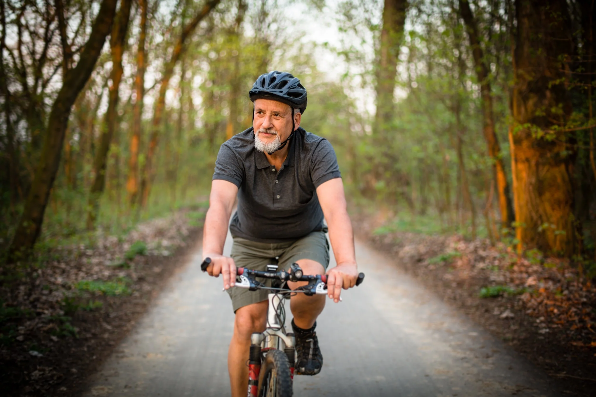 A 55 plus white man riding a bicycle on a trail in Fishers, Indiana.