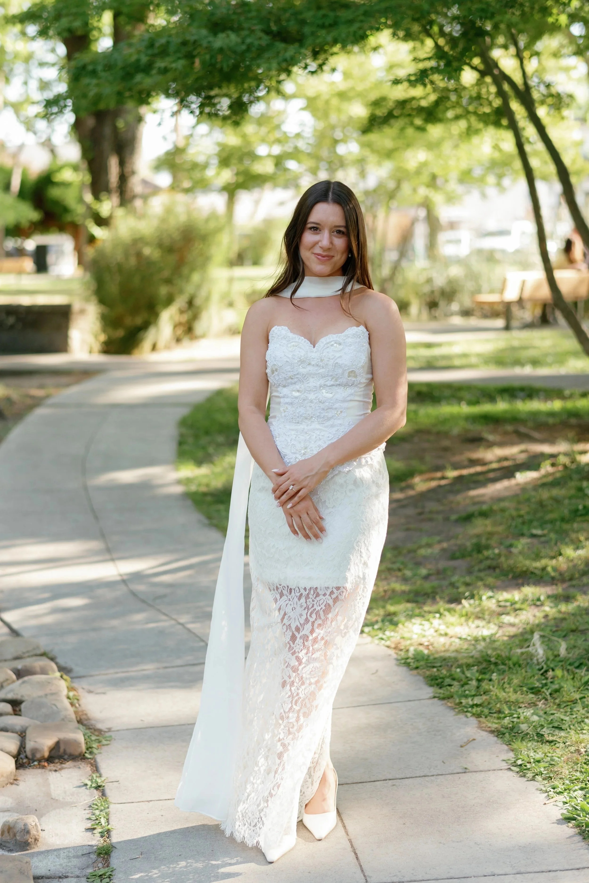 A dress form on a stand is positioned in front of a window with sunlight shining through. There is a potted plant next to the dress form on the right side.