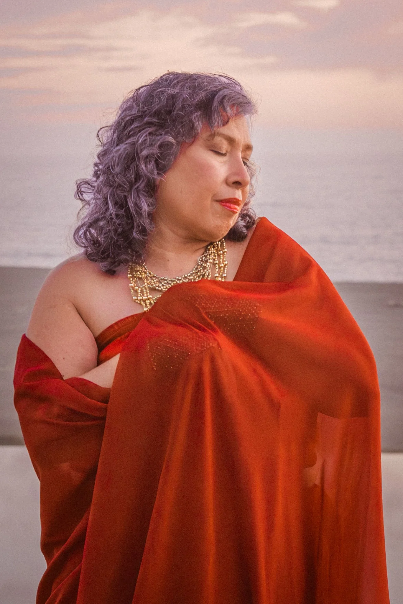 Veenaa Saynana Dolphin Heart Alchemy standing with eyes closed on a beach at sunset.