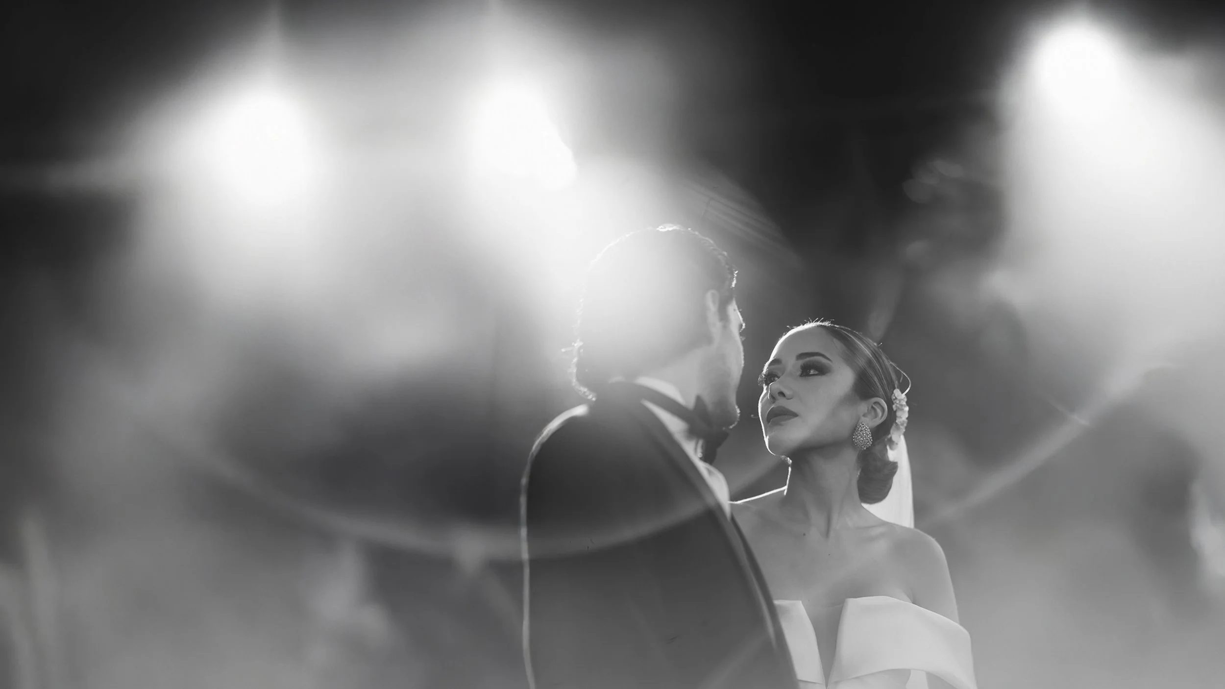Pareja de novios en una ceremonia de boda, con el novio de espaldas y la novia mirando fijamente, en blanco y negro.