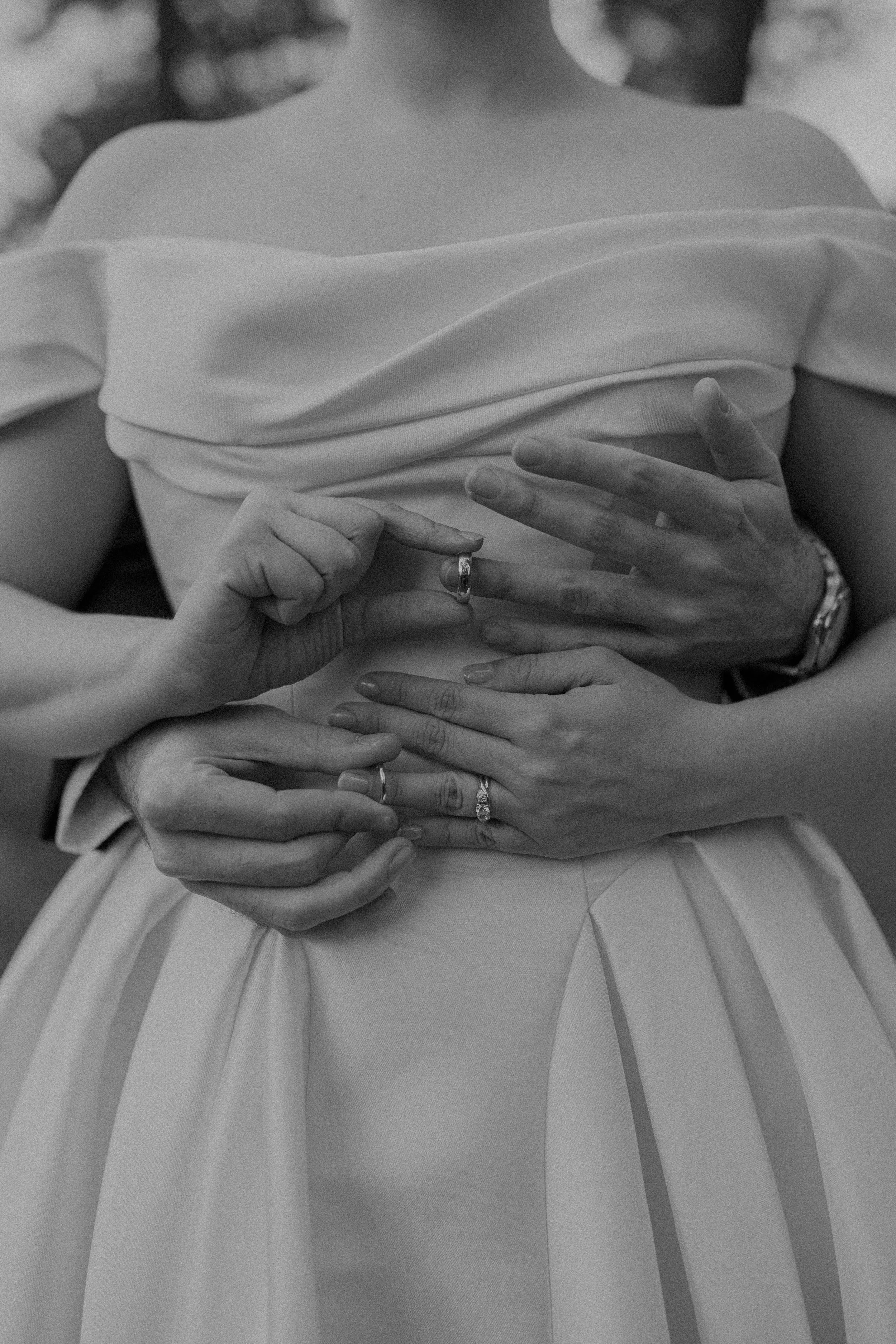 Personas mostrando y tocando anillos de compromiso y matrimonio en sus manos, en celebración de una boda, en una foto en blanco y negro.