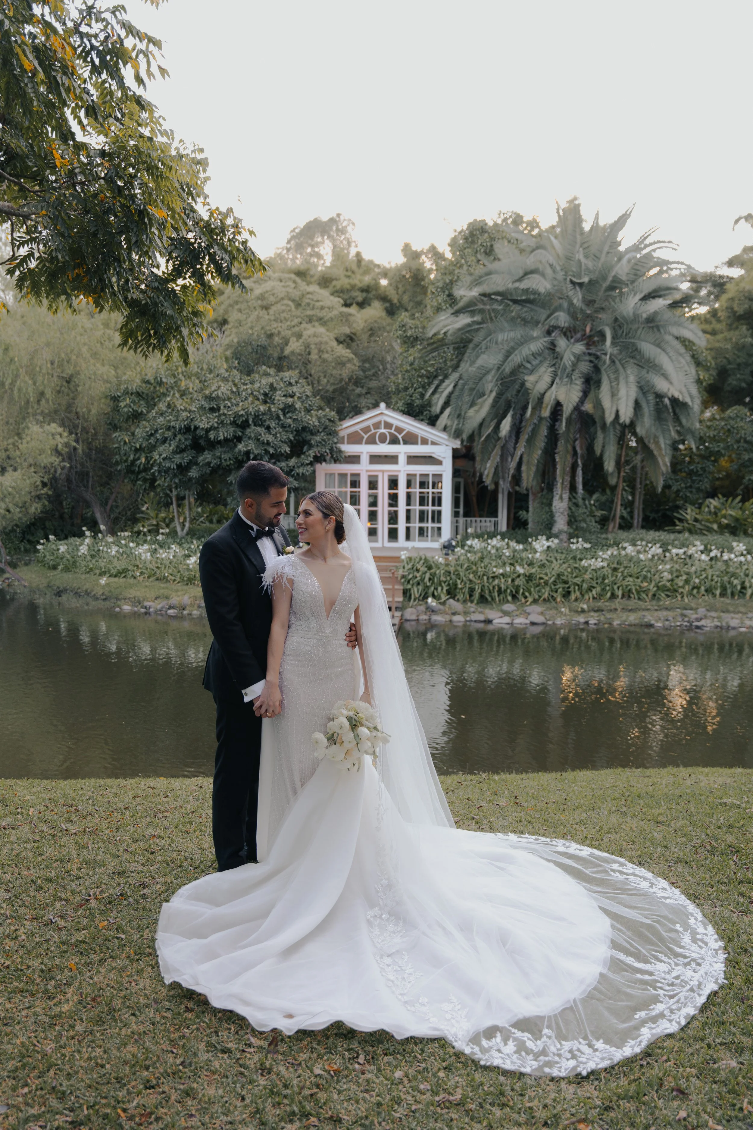 Pareja de recién casados en jardín con estanque y palmeras, ceremonia de bodas.