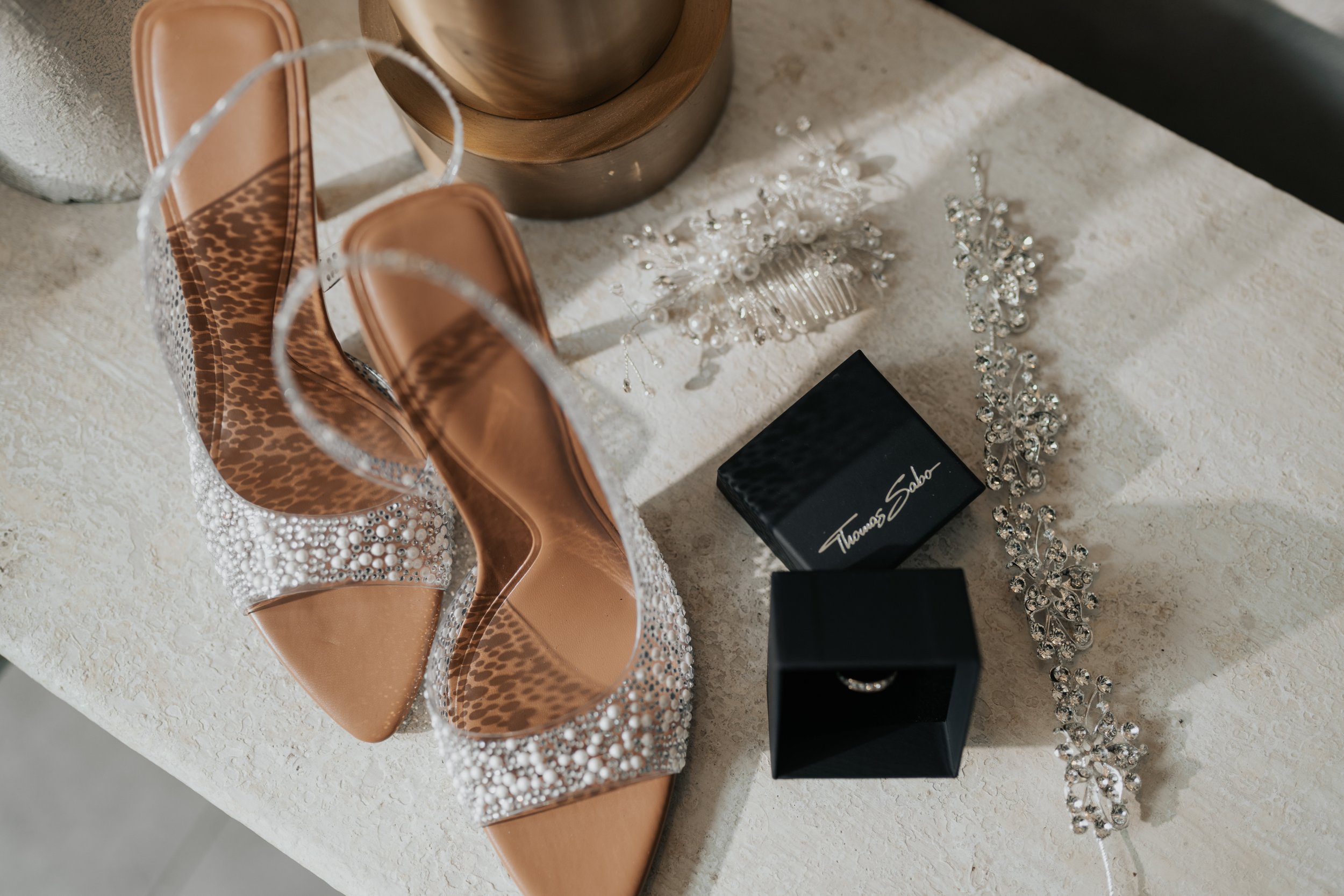 Zapatos de tacón con aplicaciones de pedrería, una caja de anillo de compromiso, accesorios de cabello con perlas y cristales, y un collar de perlas y cristales