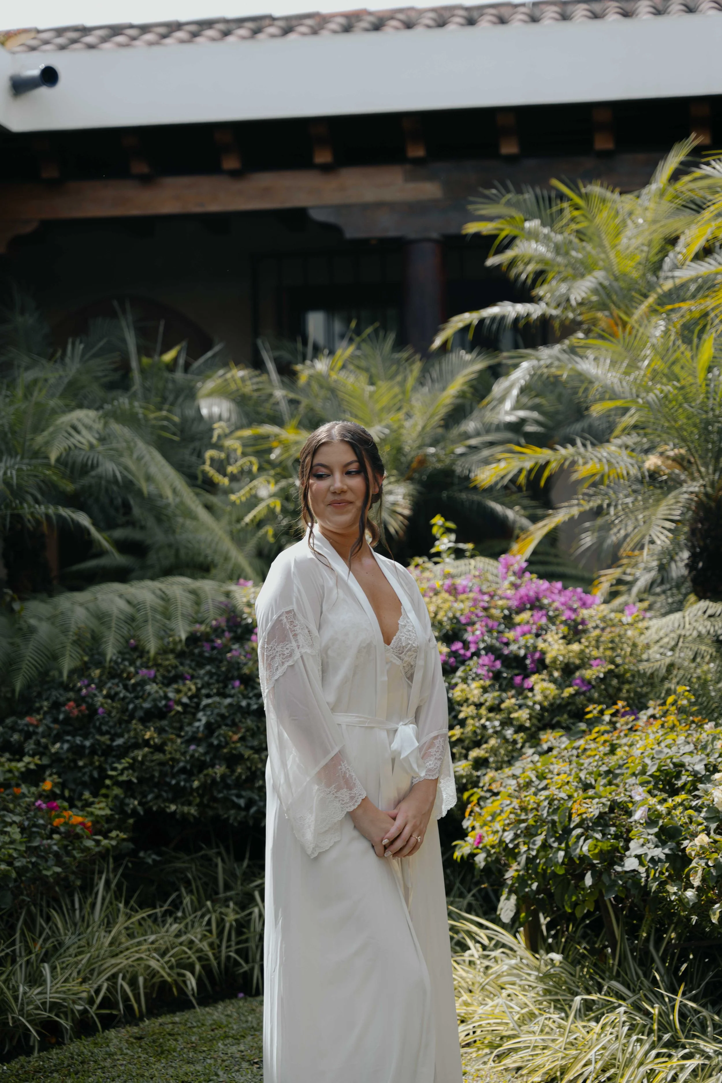 Mujer vestida con un vestido de novia en un jardín con muchas plantas y flores.