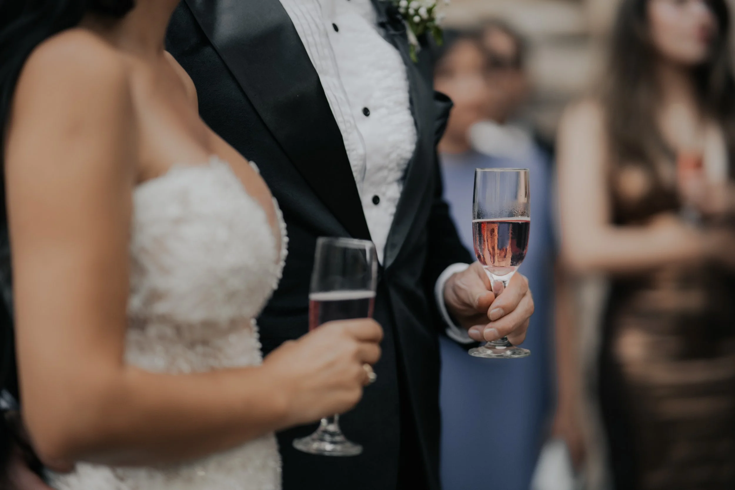 Pareja en boda sosteniendo copas de vino rosado.