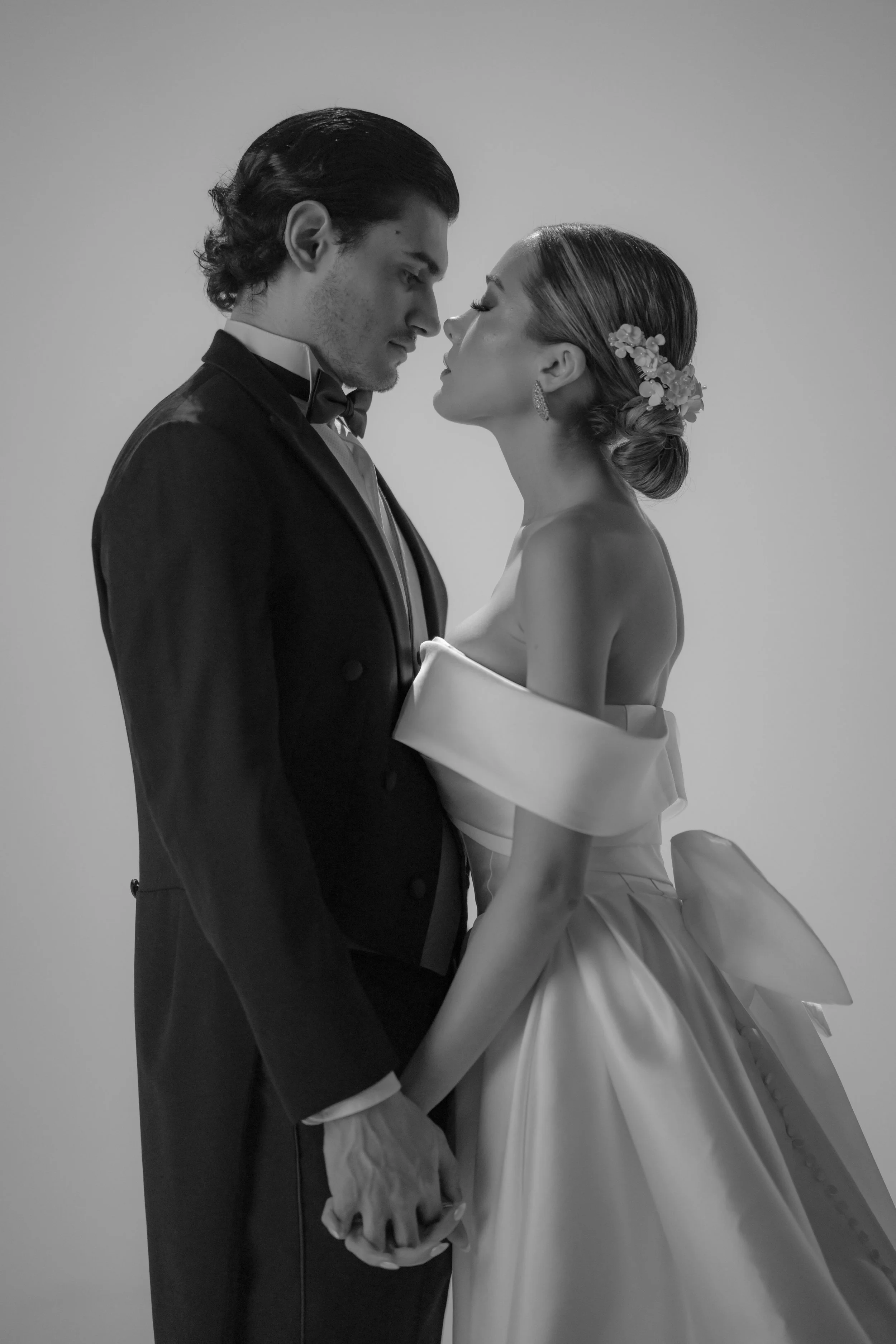 Una pareja de novios en boda, en un retrato en blanco y negro, mirándose con las frentes juntas y las manos entrelazadas.