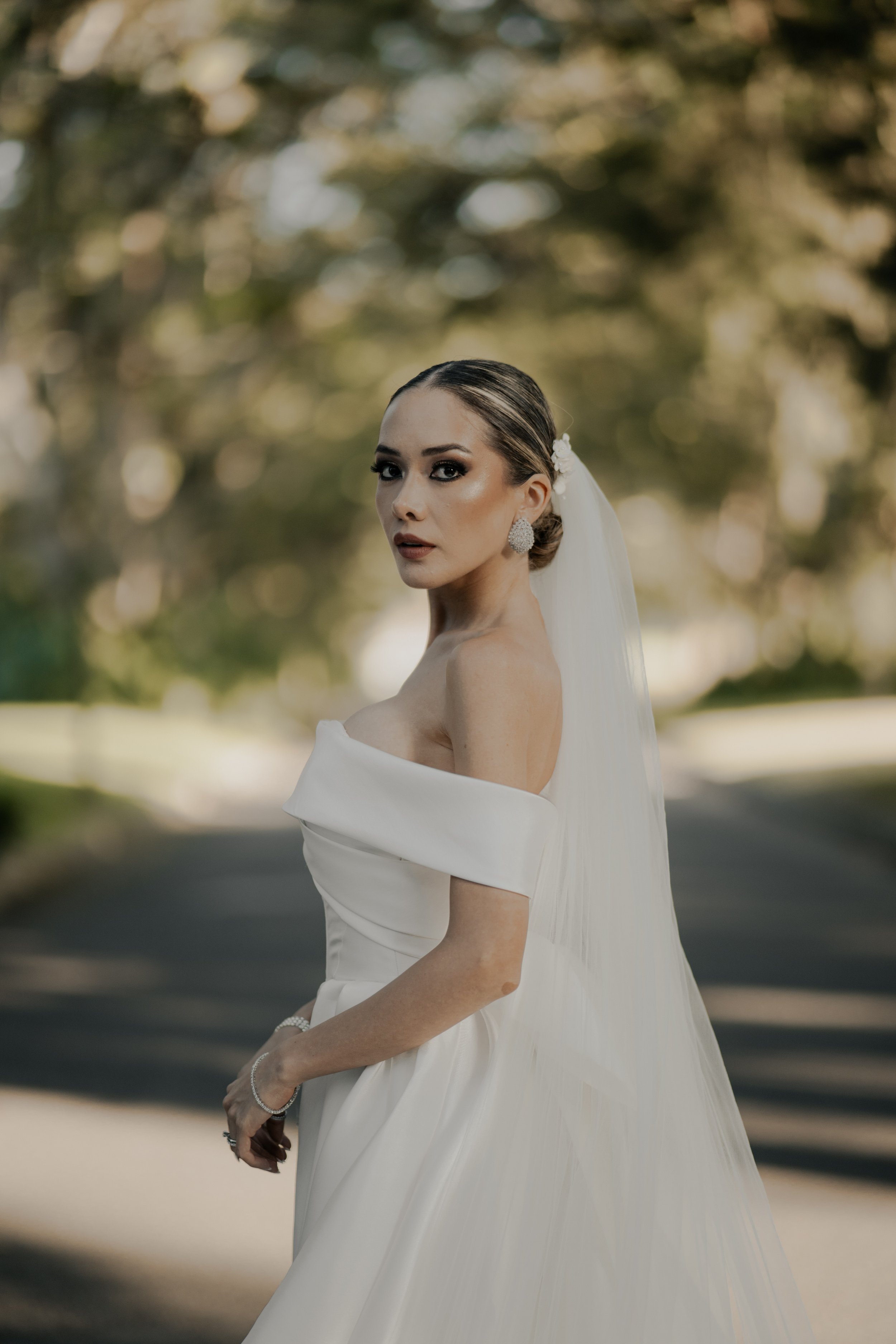 Mujer en vestido de novia con fondo de árboles.