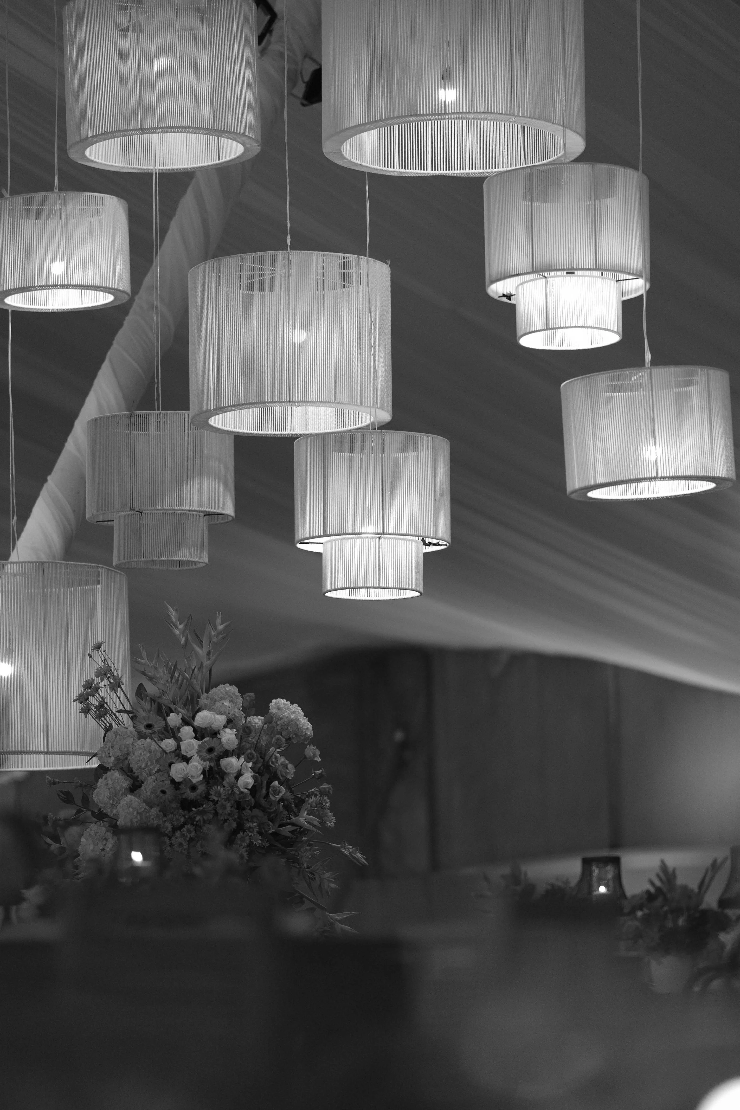 Lámparas de techo colgantes en el interior de un lugar elegante, con un ramo de flores visible en primer plano.