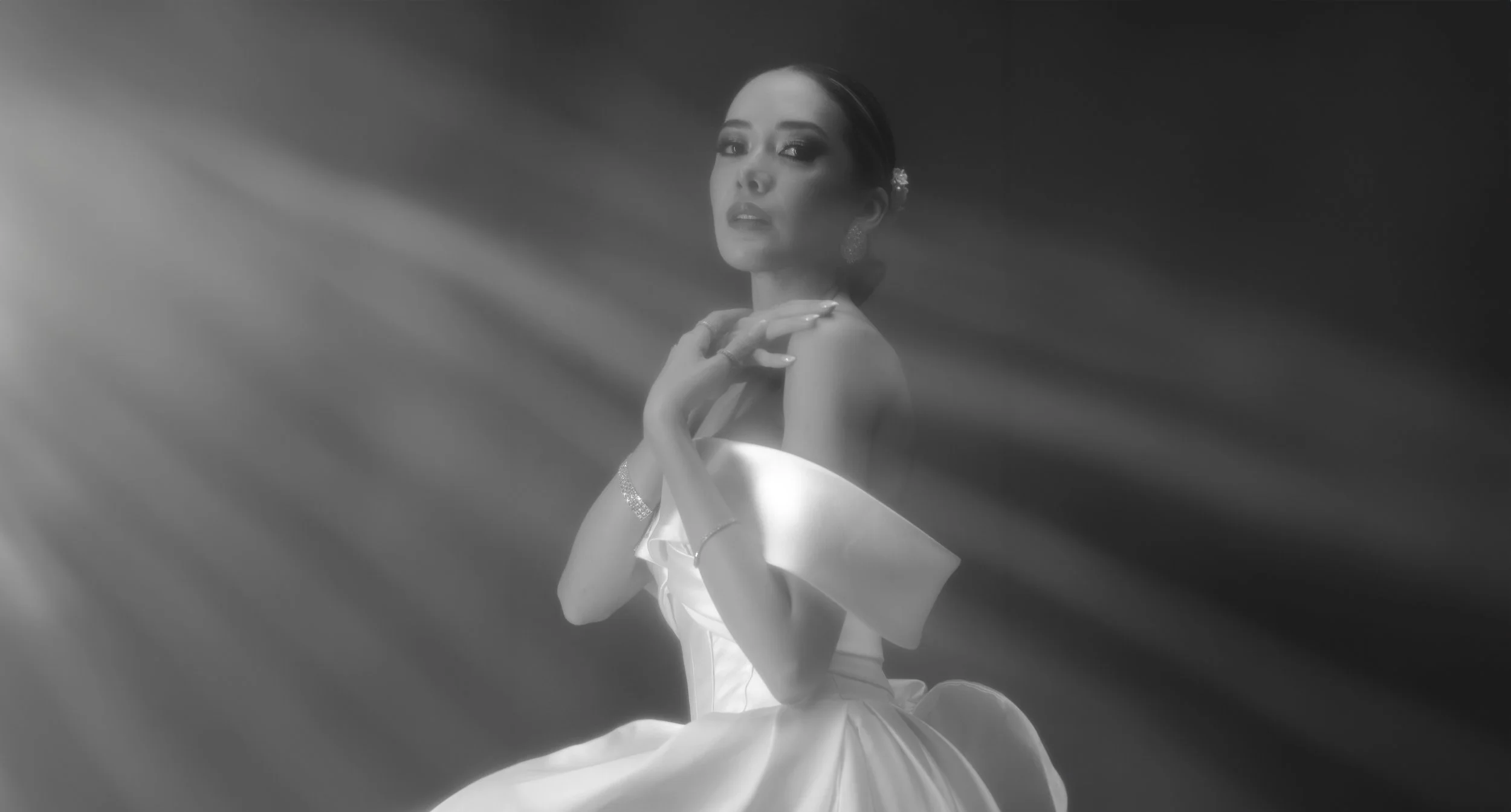 Mujer en vestido de novia posando en un fondo oscuro con luces suaves.