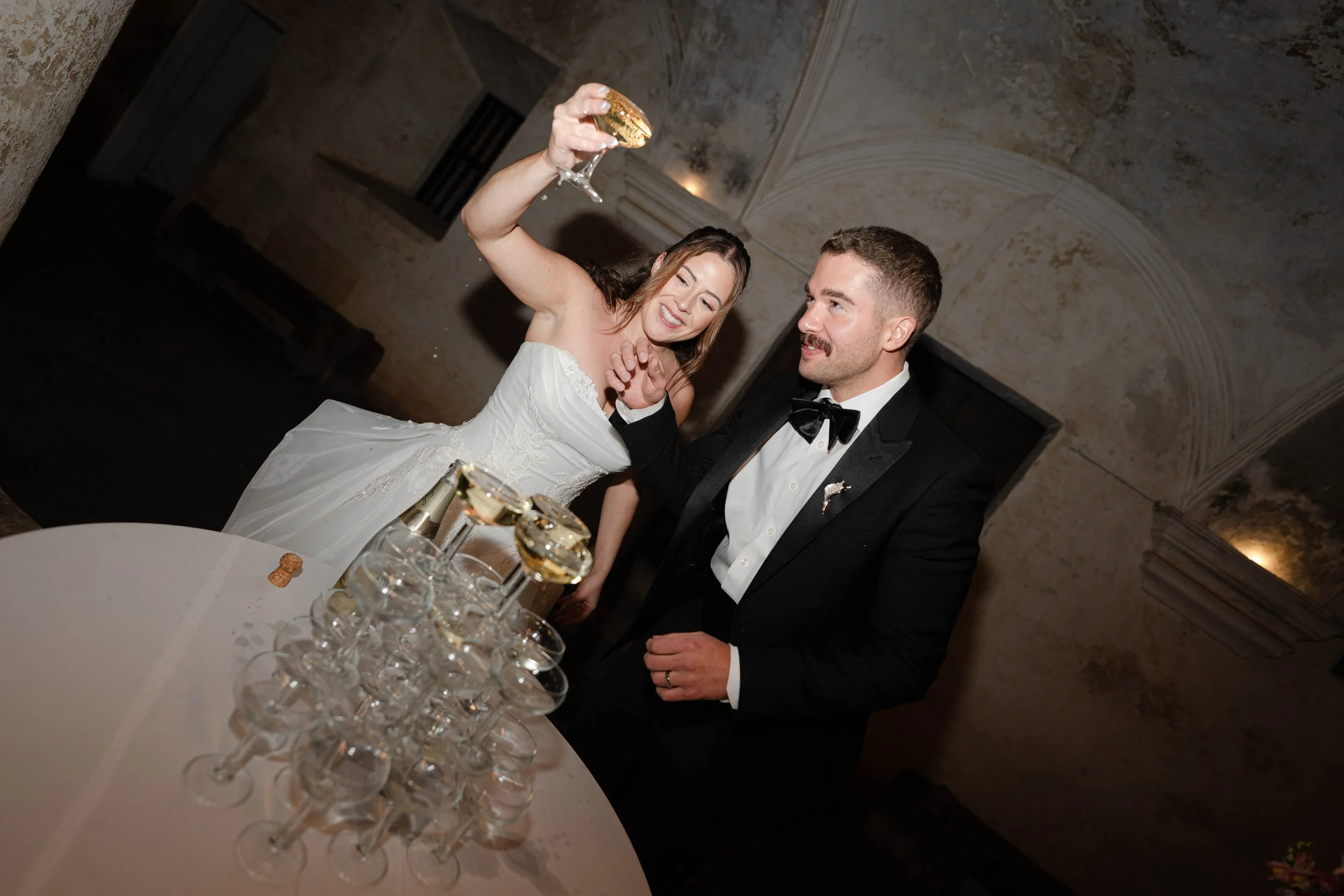 Una pareja vestida de boda brindando con copas de champán en una celebración elegante.
