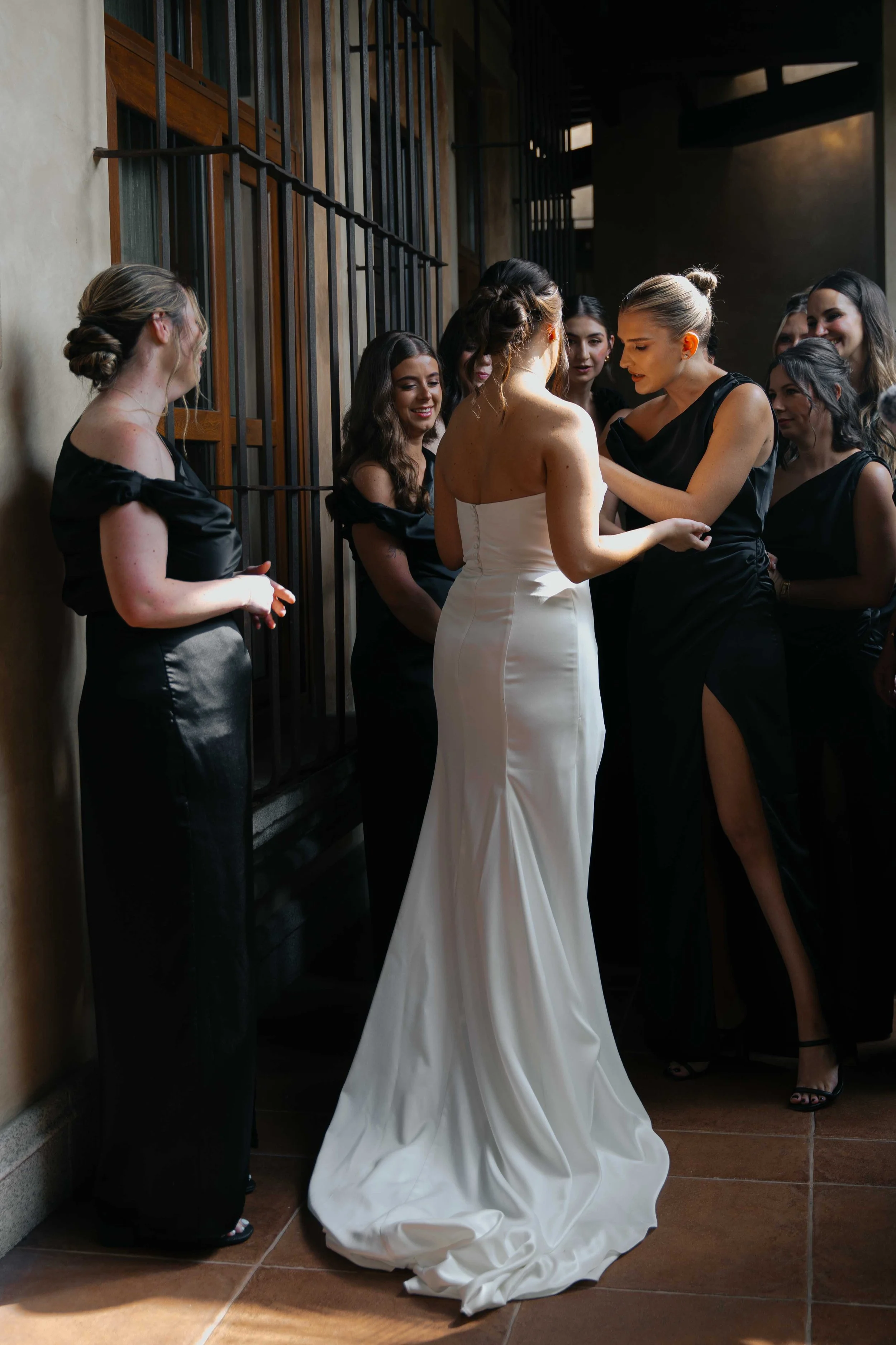 Mujer de vestido de novia rodeada de amigas en una preparación previa a la boda.