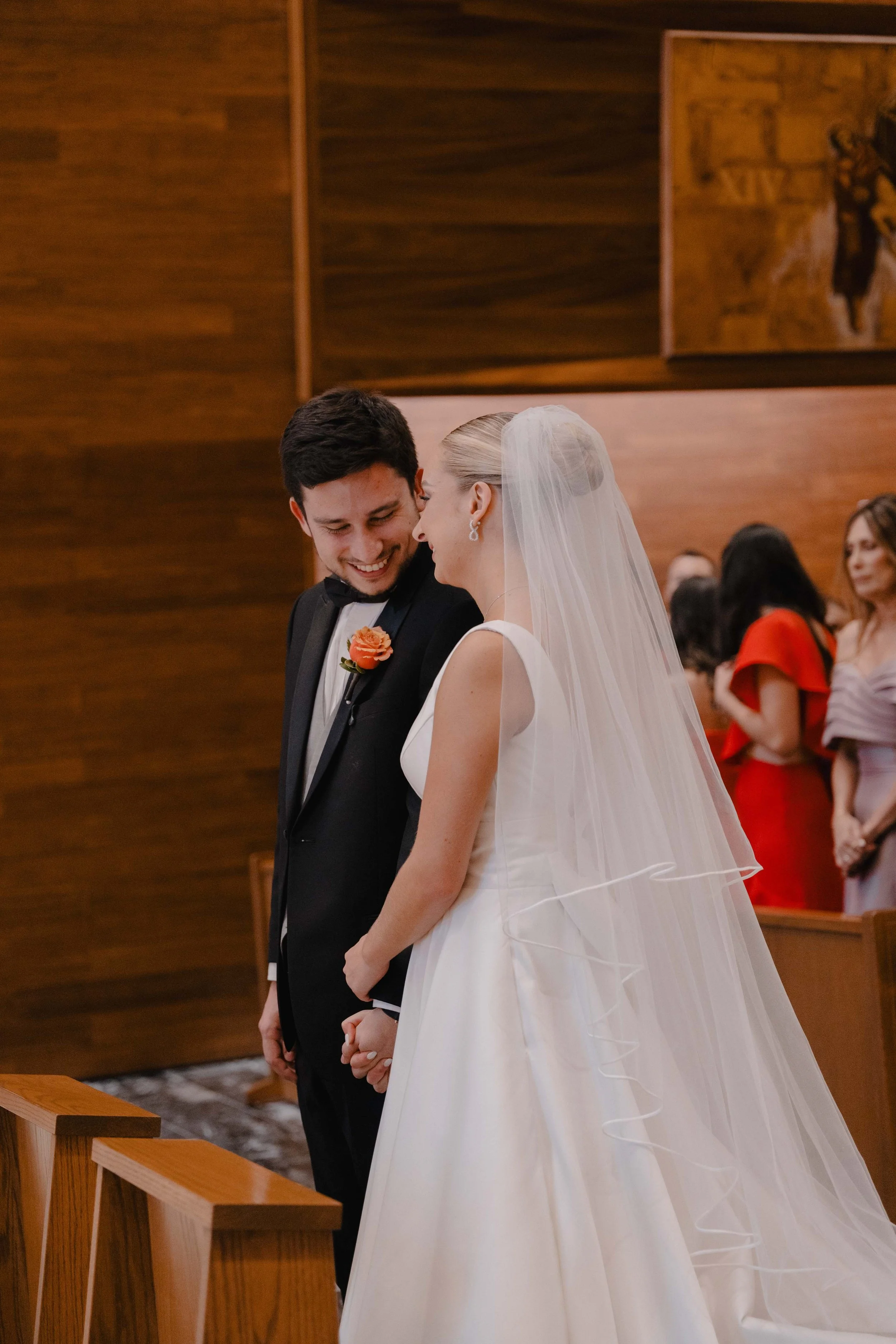 Pareja de novios en una boda, sonriendo y tomados de la mano en la iglesia