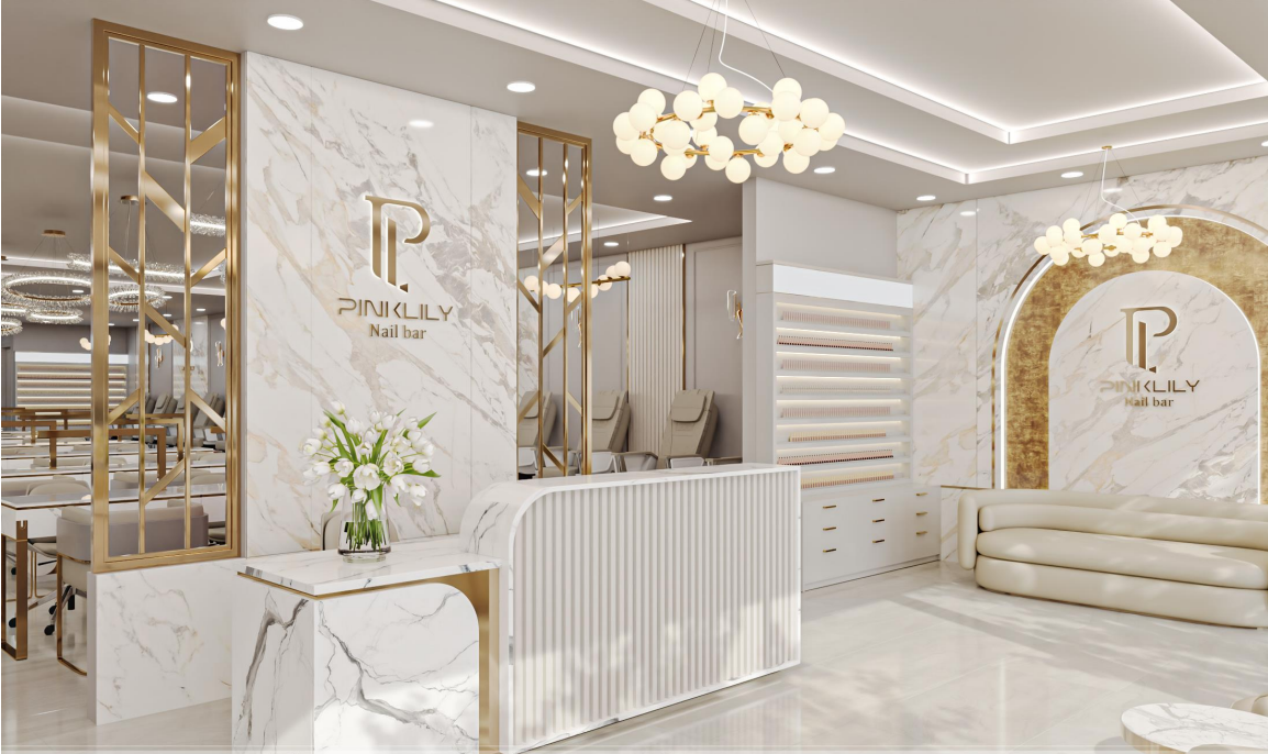 Interior of a luxury nail salon with white marble decor, gold accents, modern chandelier lighting, and seating area.