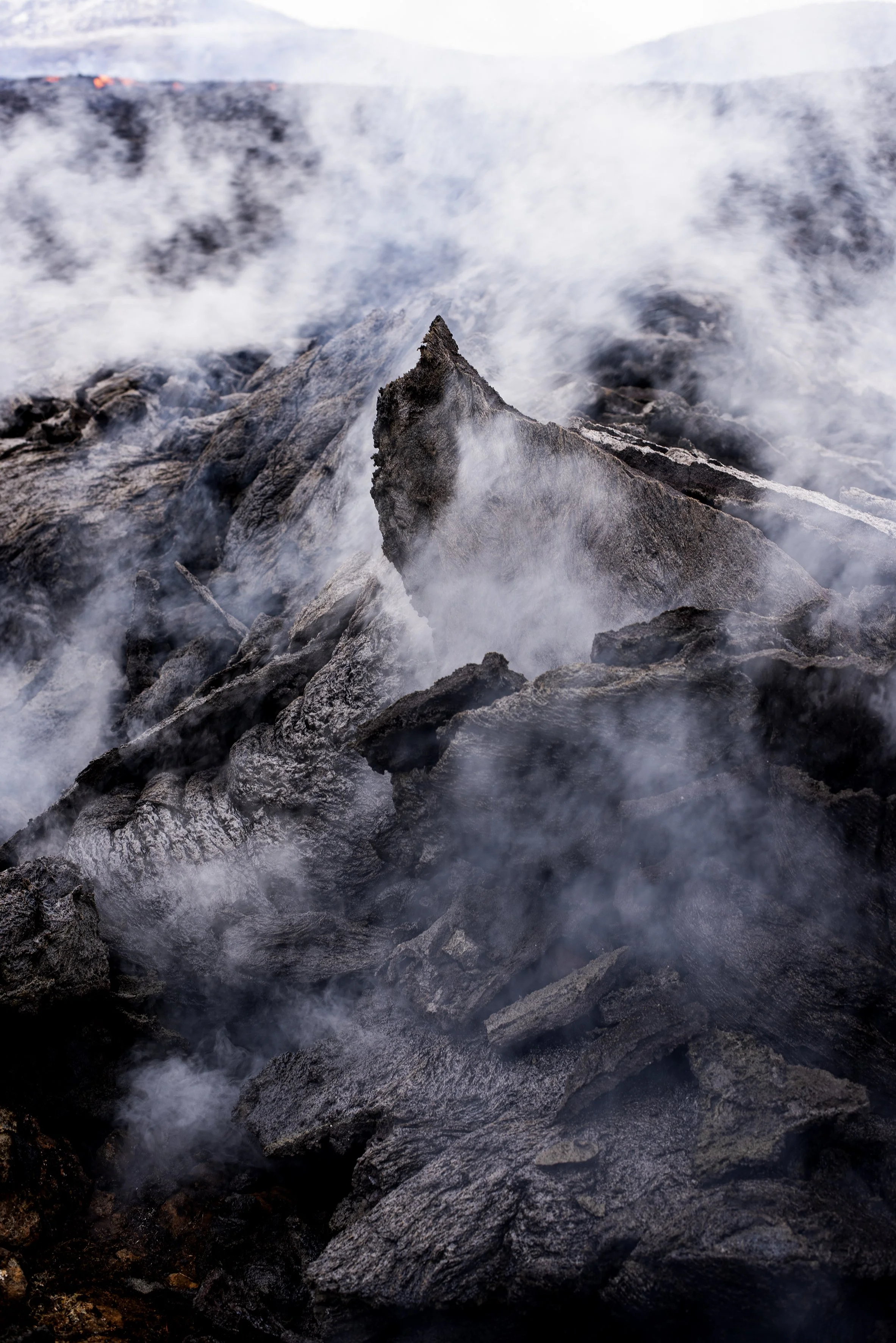 Lava rocks with smoke rising from volcanic activity.