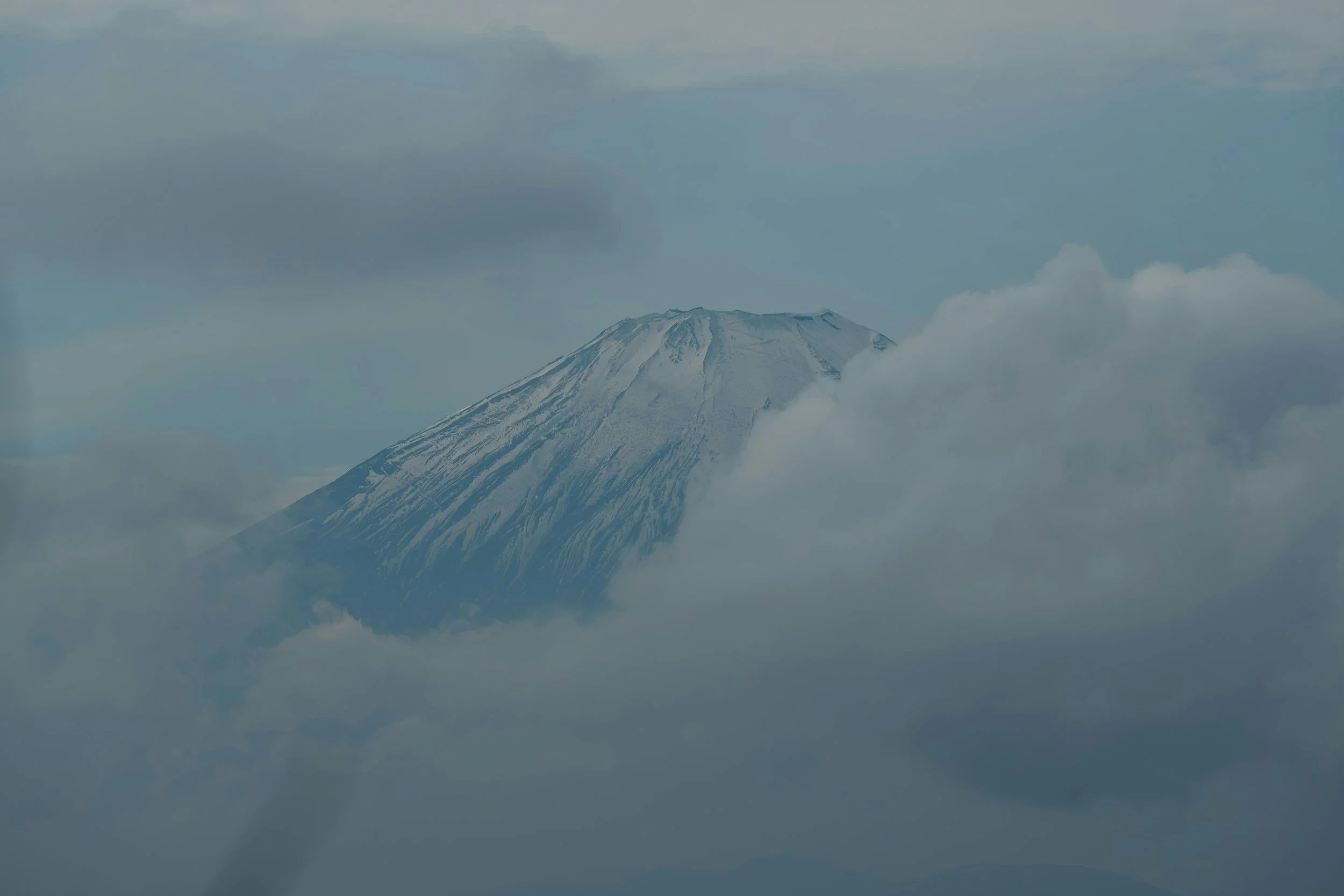 Mount Fuji partially obscured by clouds with a snow-capped peak.