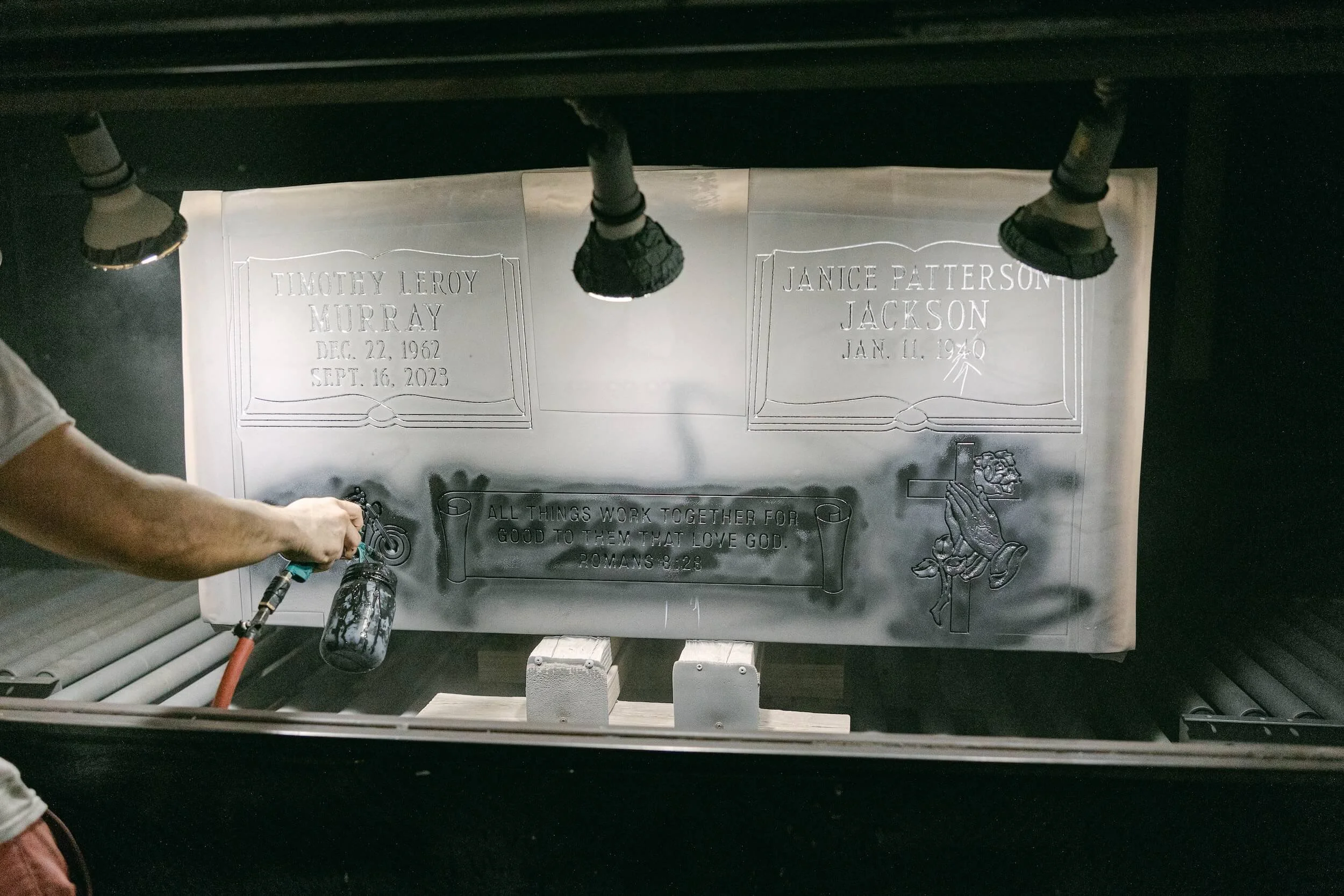 Ublast blasting with black paint on headstone with a Ublast stencil on it