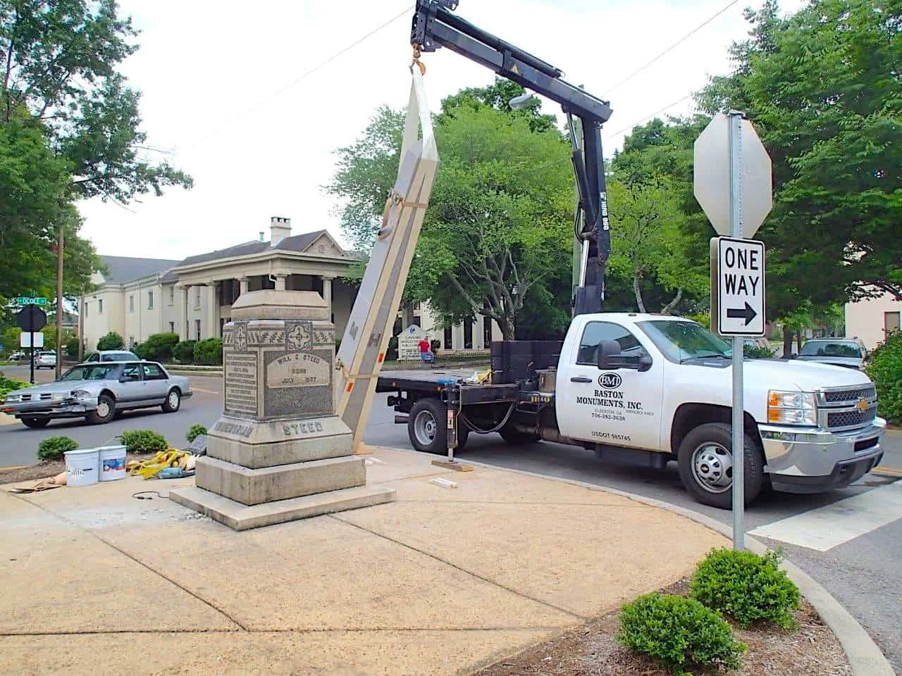 town-setting-with baston-mounuments inc. truck installing a statue