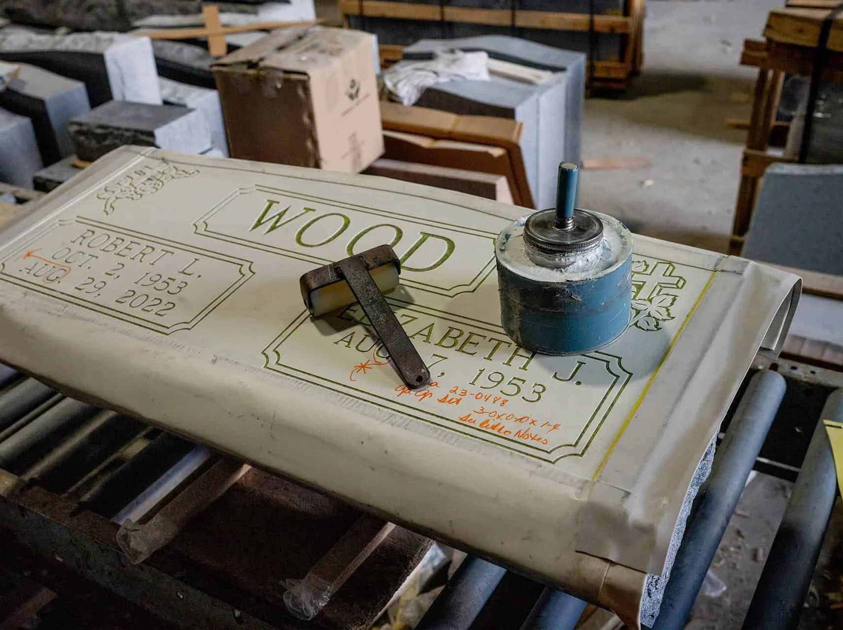 A ublast headstone stencil with glue and a roller sitting on it in a production shop