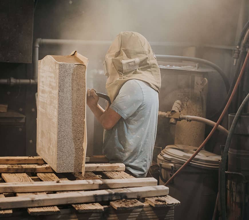 A man sandblasting a granite headstone