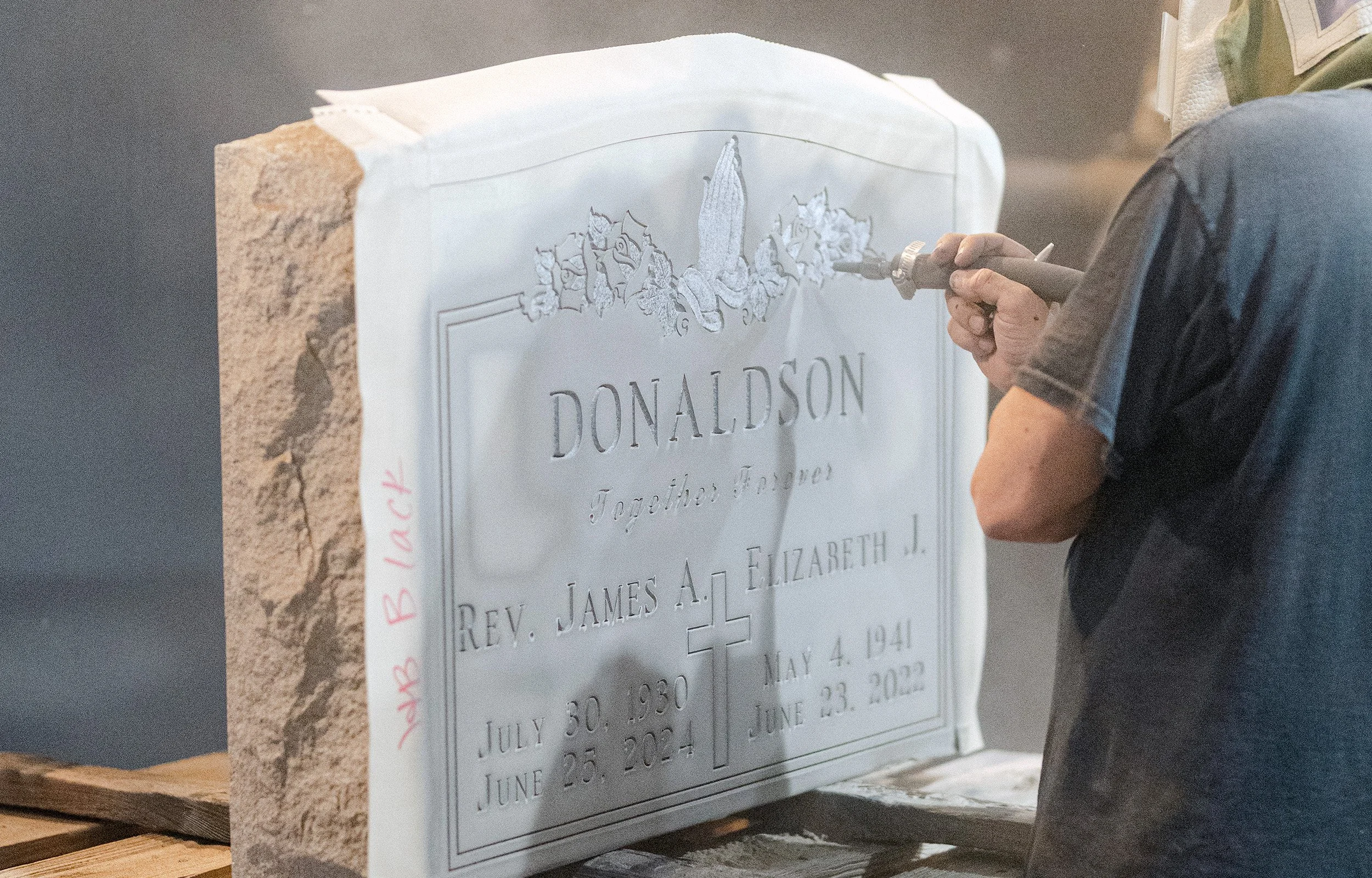 A man sandblasting a headstone with a Ublast stencil on it