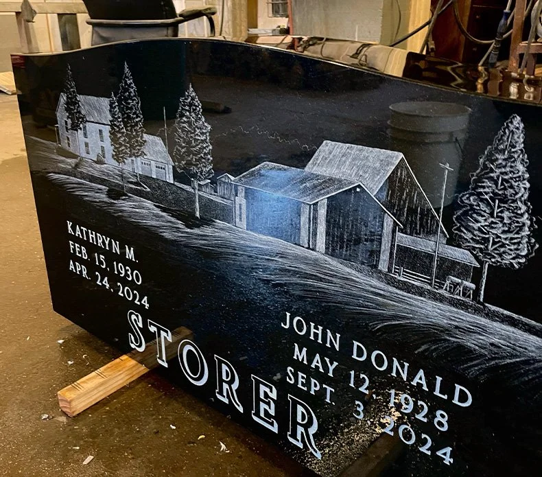 A headstone with a beautiful farm scene designed by Peebles Monuments Co.