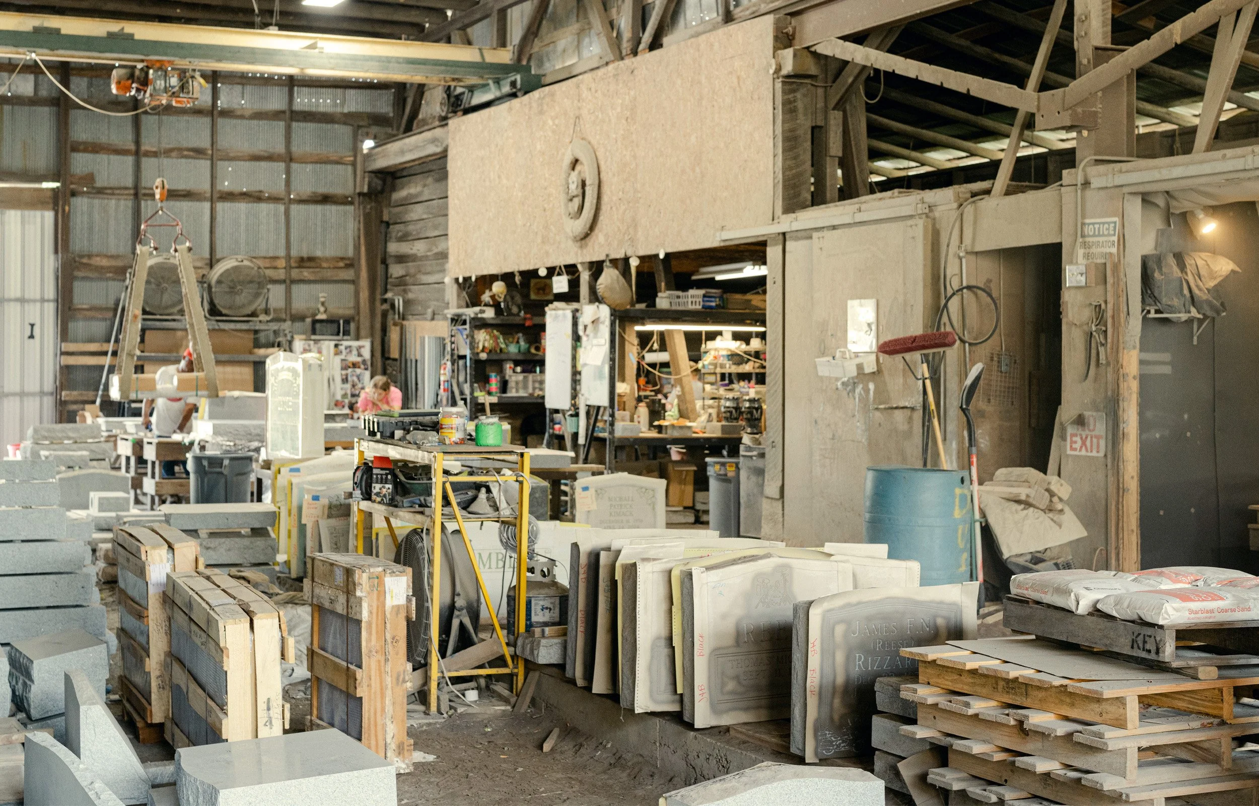 A scene of a monuments workshop filled with blank and etched stones