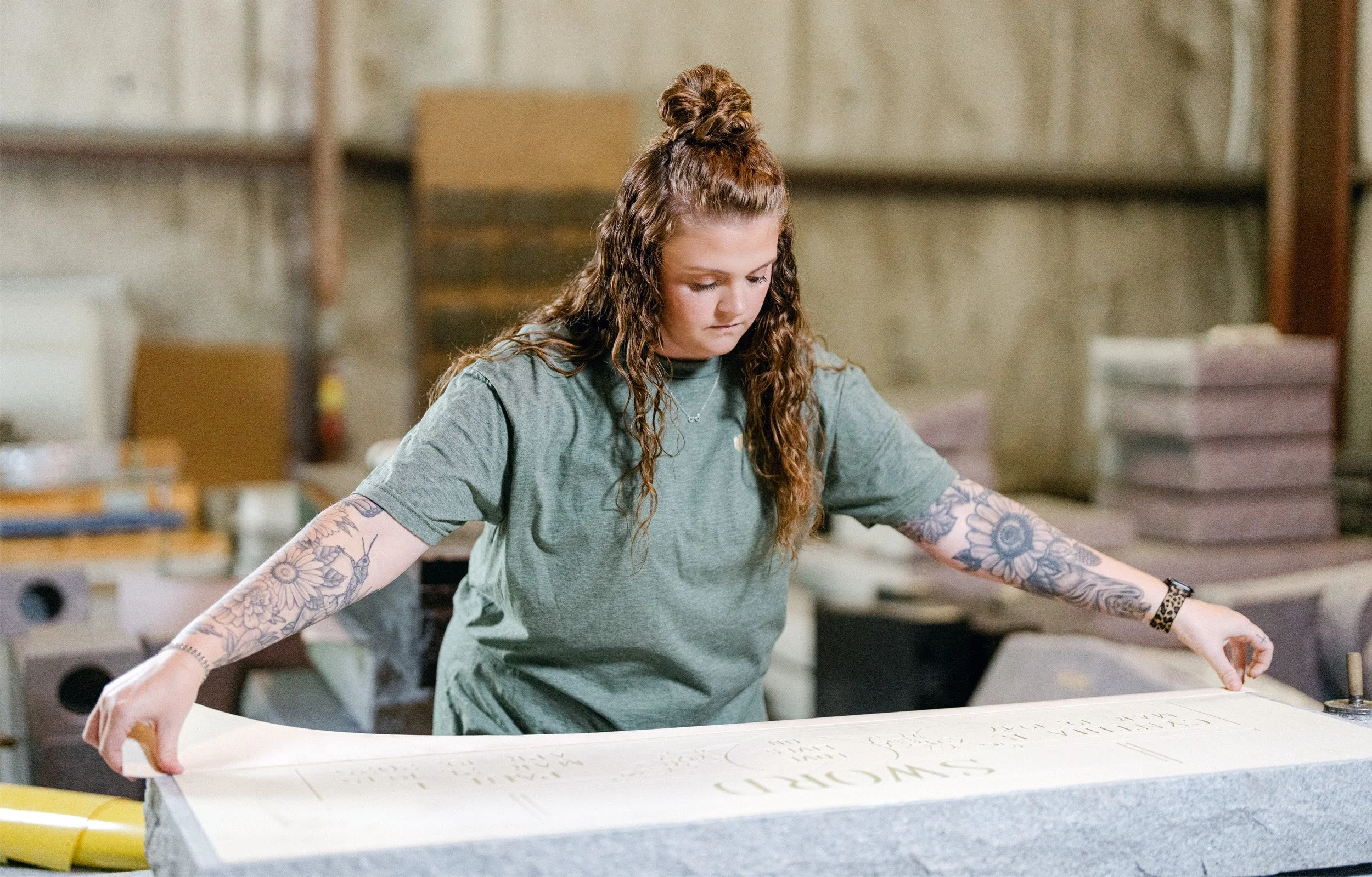 A woman adhering a rubber stencil to a granite headstone