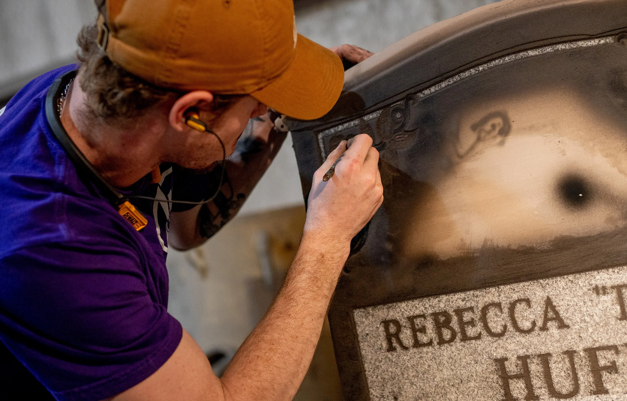 A man applying details to a headstone.