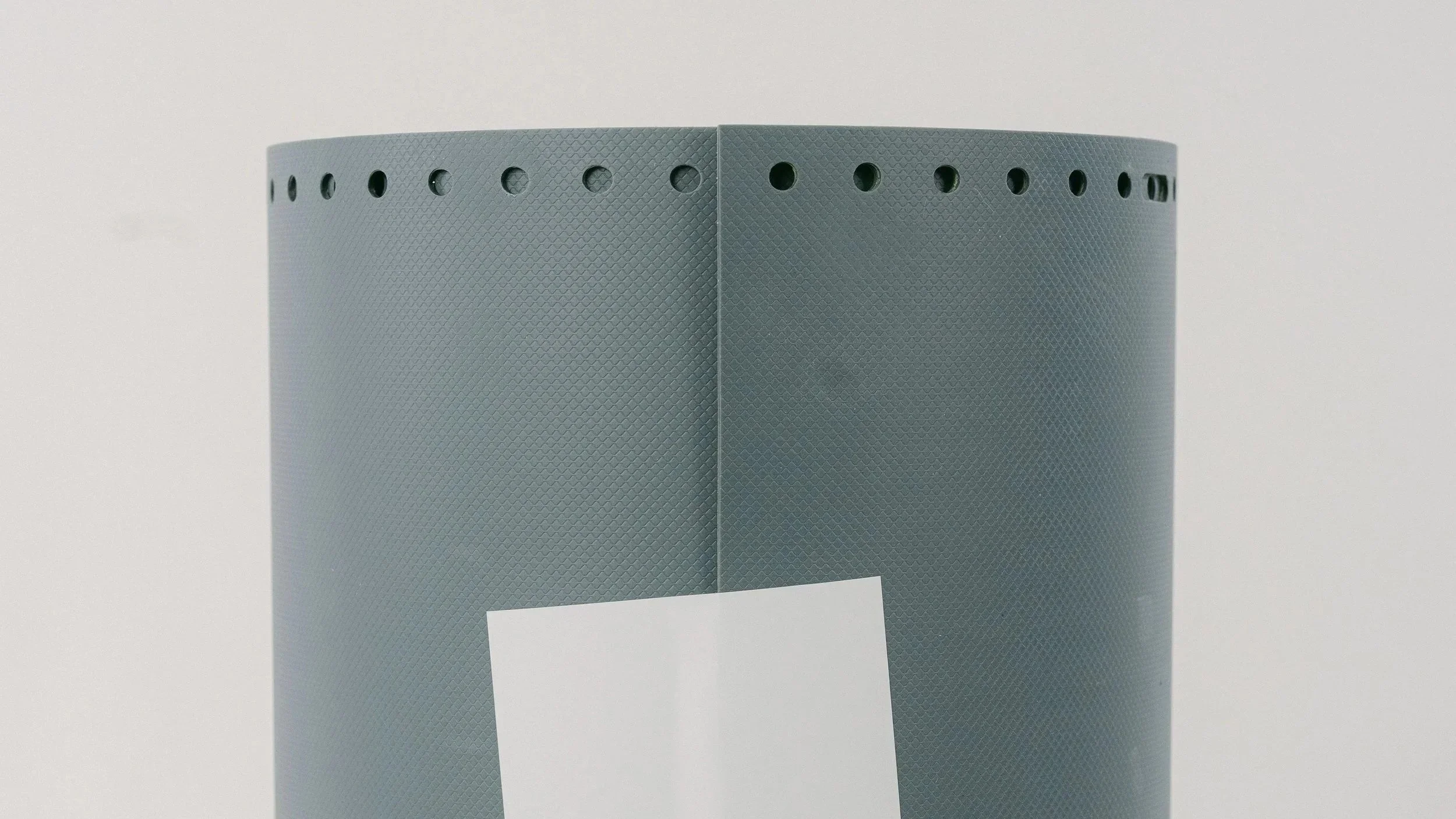 A ublast stencil product in slate color roll standing up on with plain background and a white sticker on it