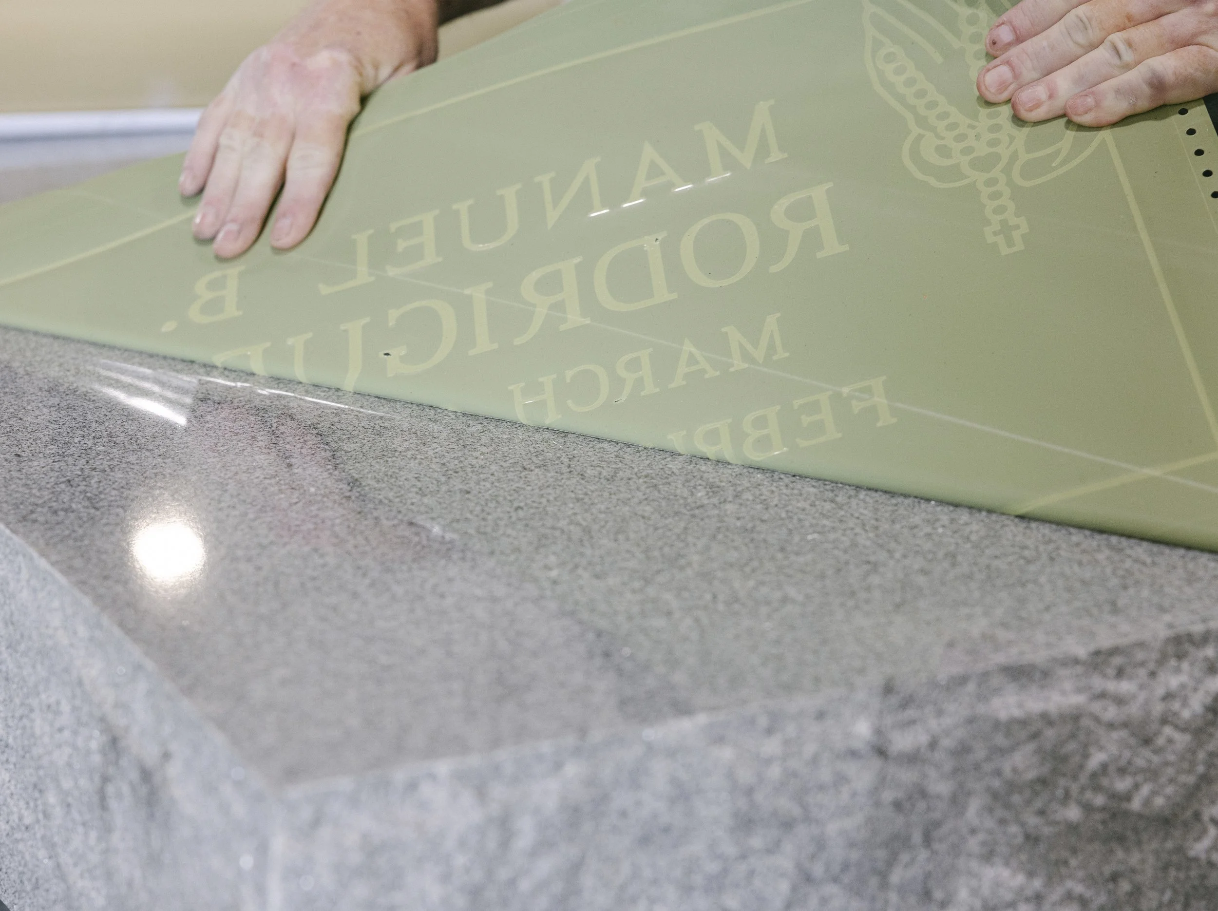 A man peeling back or placing a stencil on granite