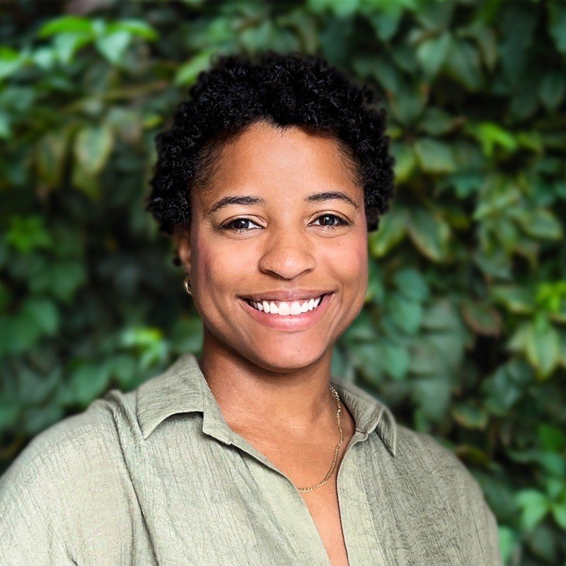 Portrait of a woman with black hair, wearing a sage green shirt.