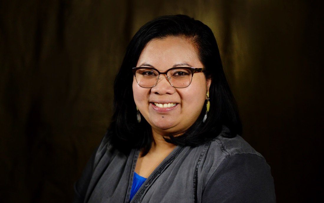 A woman with long black hair smiling confidently.