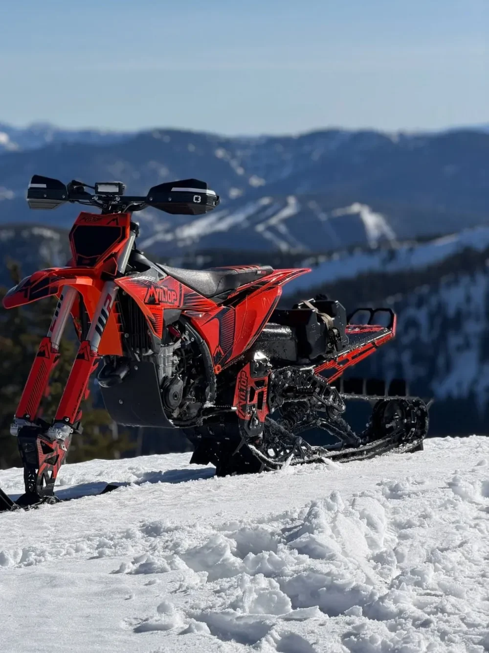 Red MTN.TOP snowbike overlooking a mountain valley
