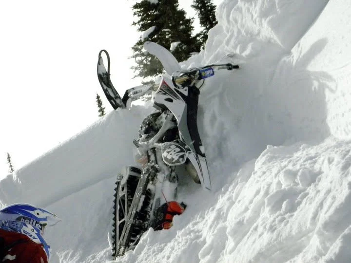 Snowbike standing nearly vertical in deep powder