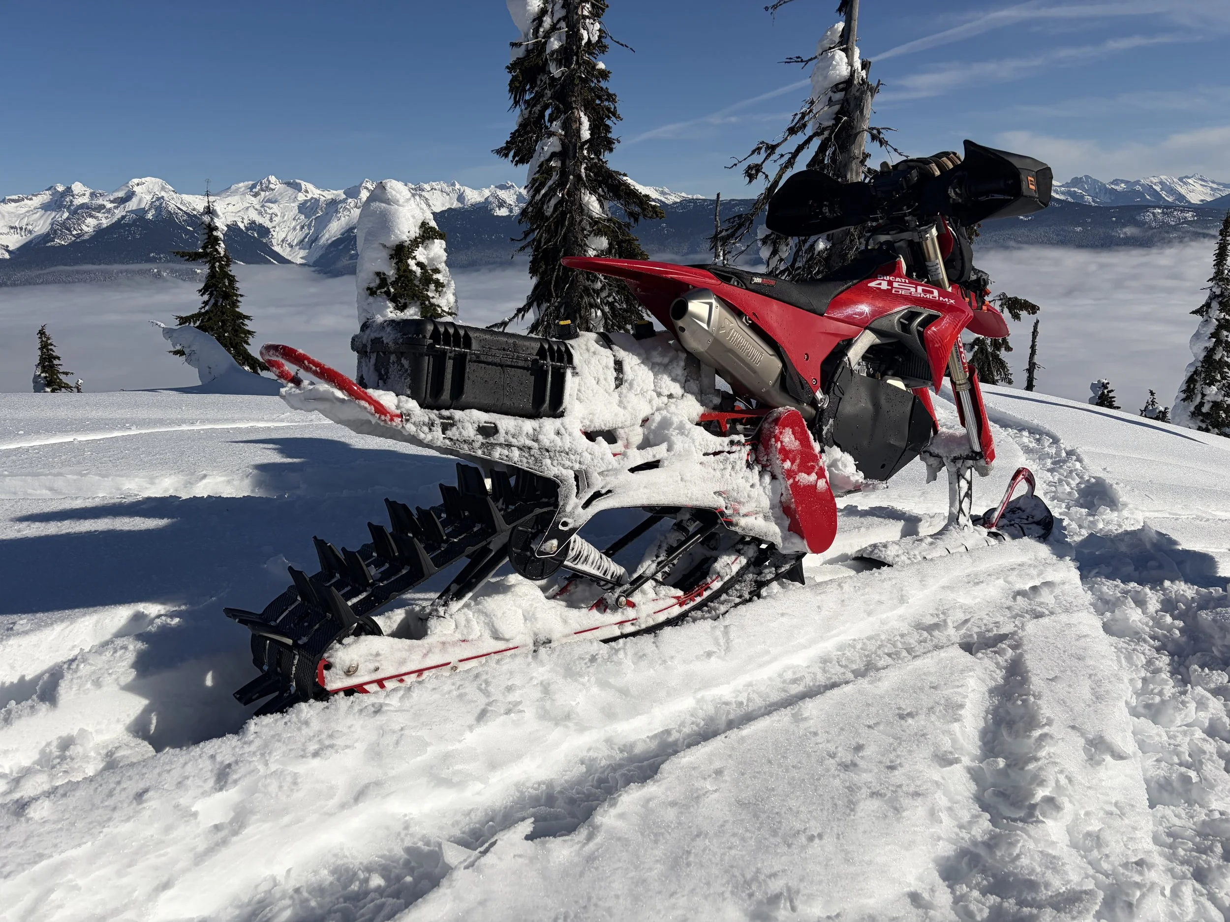 Rear three-quarter view of John Getkate’s 2026 Ducati Desmo450 MX and CMX Dominator 126, showing the track, tunnel, cargo box and mountain setting.