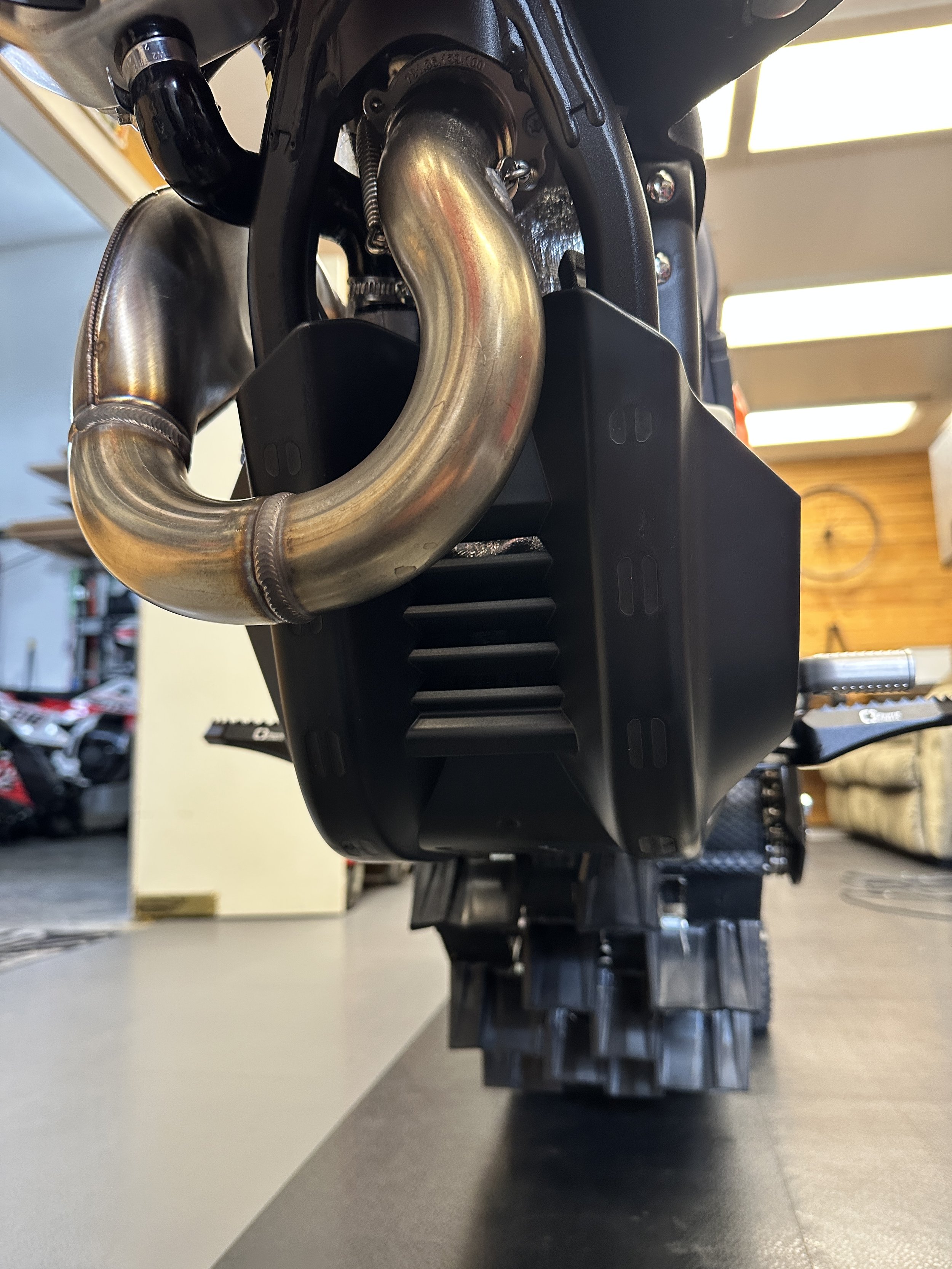 Front and underside view of installed KTM OEM skid plate below the exhaust