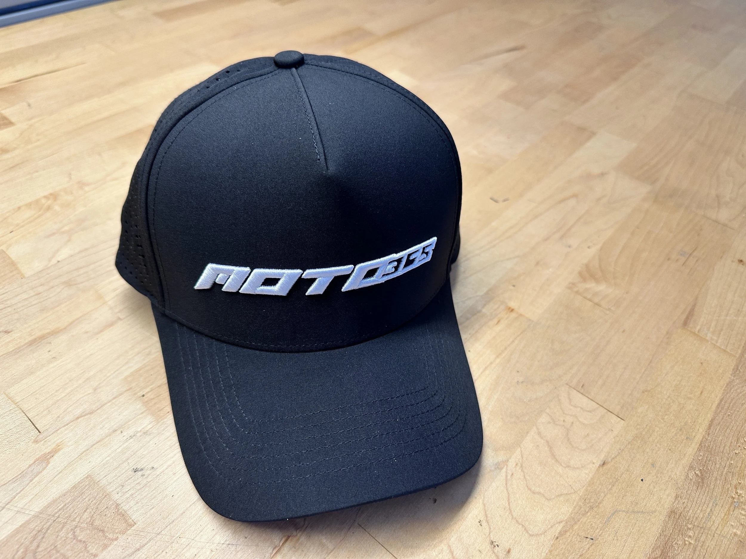 Black Moto365 performance snapback hat with curved bill and raised white front embroidery, built by MtnTop.