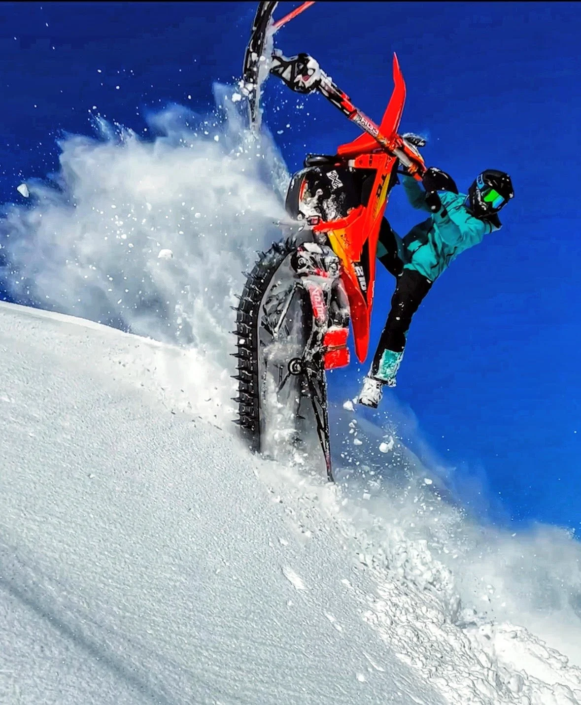 Snowbike rider performing a wheelie in deep powder